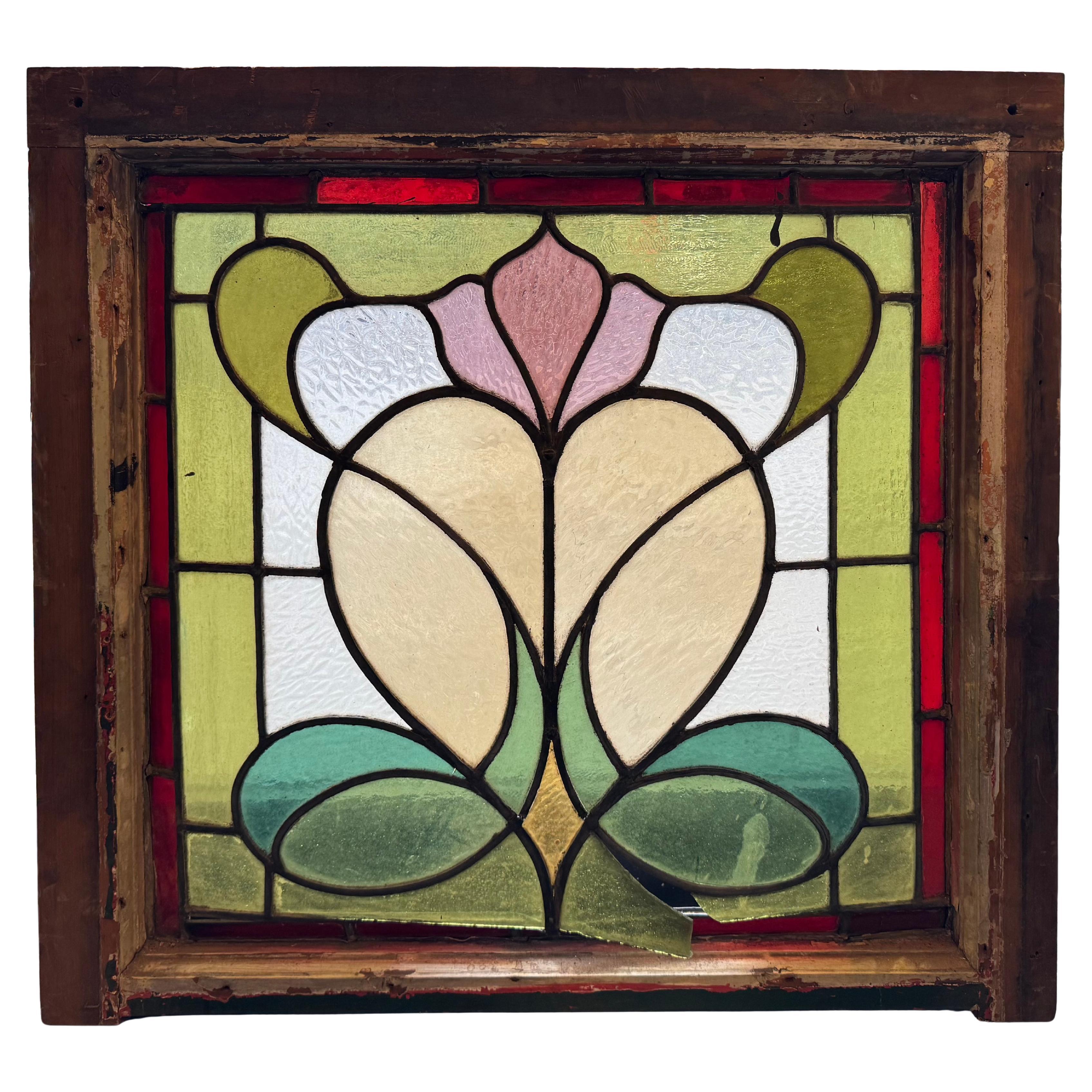 Esta ventana de bello diseño presenta un motivo Art Nouveau de una flor saliendo de un corazón. ¡Los colores están en muy buen estado! 
Las dimensiones totales corresponden a la vidriera y el marco.
Situado en NY