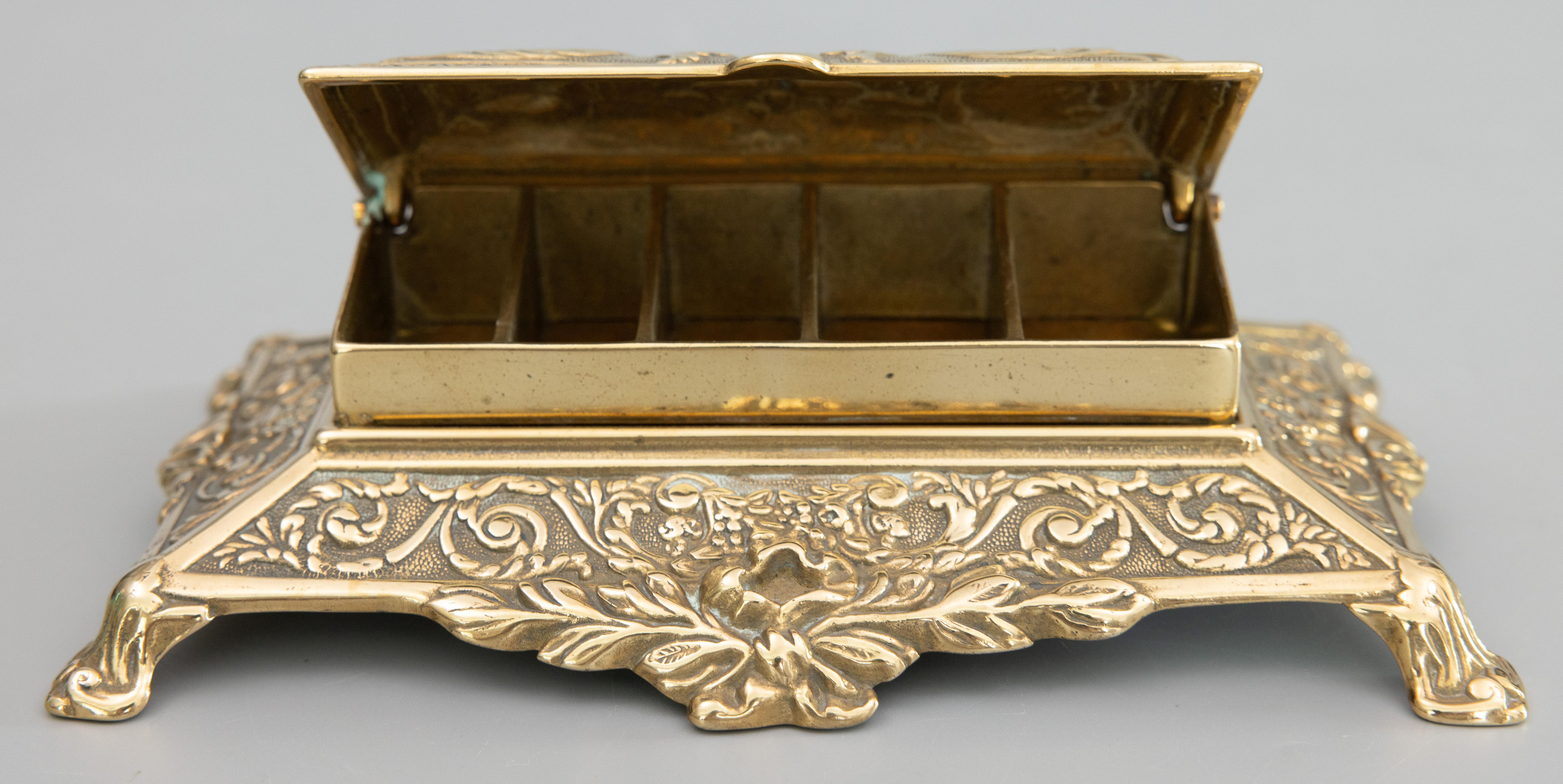 A superb antique English Art Nouveau cast brass desktop footed stamp box with a lovely brass patina, circa 1920. This fine box has an ornate Neoclassical design and scrolled feet with a hinged lid and five sloped compartments for stamps. It's a nice