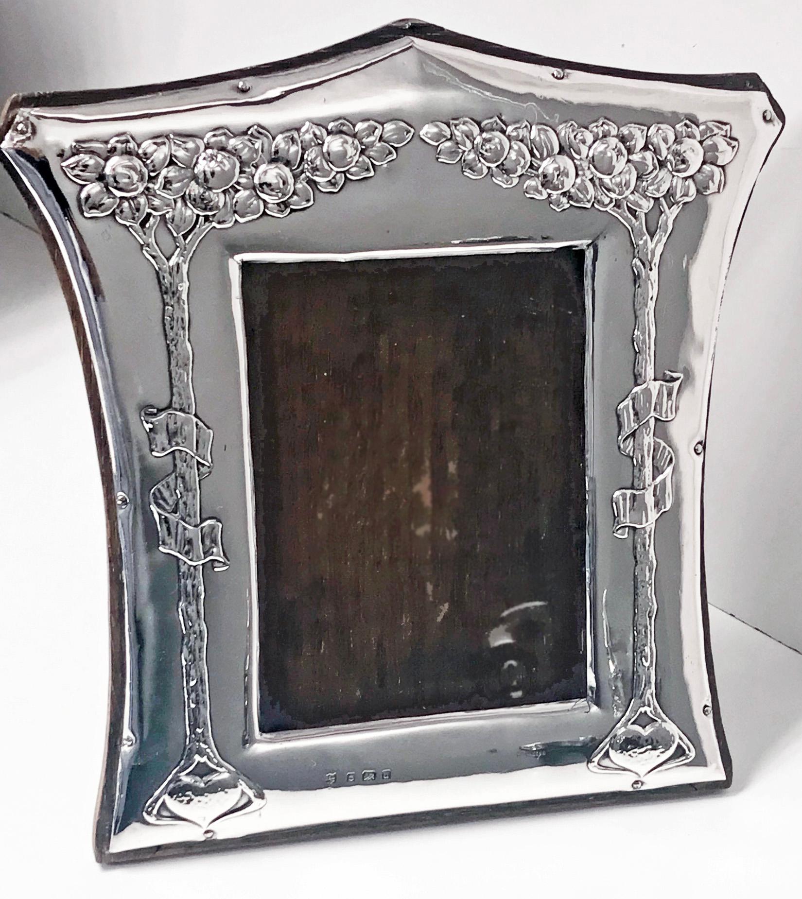 Art Nouveau English silver photograph frame, Birmingham, 1903, Charles Green. The frame decorated with oak trees, ribbons and hearts, mounted on oak with easel back. Frame measures: 8.50 x 8.125. Image size: 5 x 4 inches. Fully hallmarked.