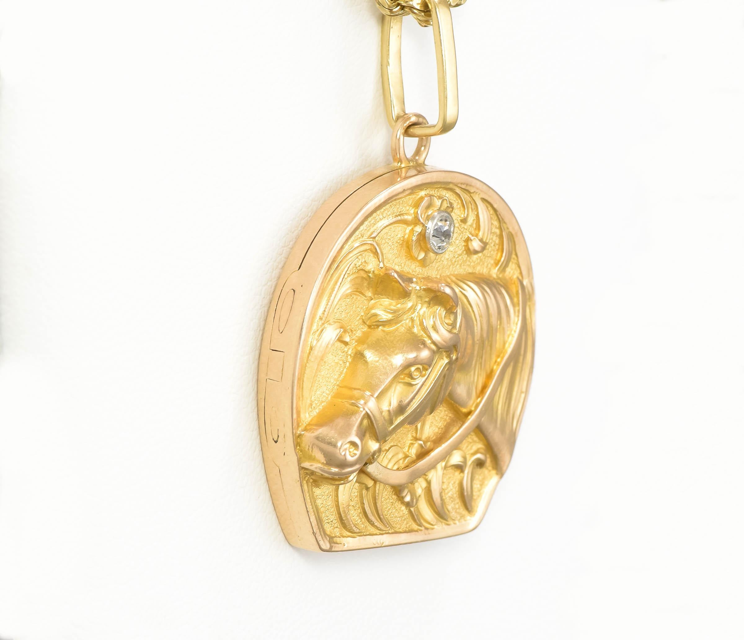 Dating to the Art Nouveau period, this superb gold horseshoe shaped locket features a very dimensional/high relief depiction of a horse surrounded by a foliate design, surmounted by a fiery old European cut diamond.  Perfect for an Equestrian or