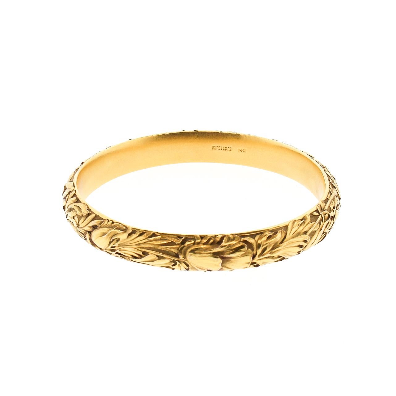 A beautifully engraved 14k yellow gold Art Nouveau bangle bracelet by Shreve and Co. The bracelet has iris and leaves and branches deeply engraved into the 14k. The motif is purely Art Nouveau, with the appreciation of nature. The bracelet is hollow