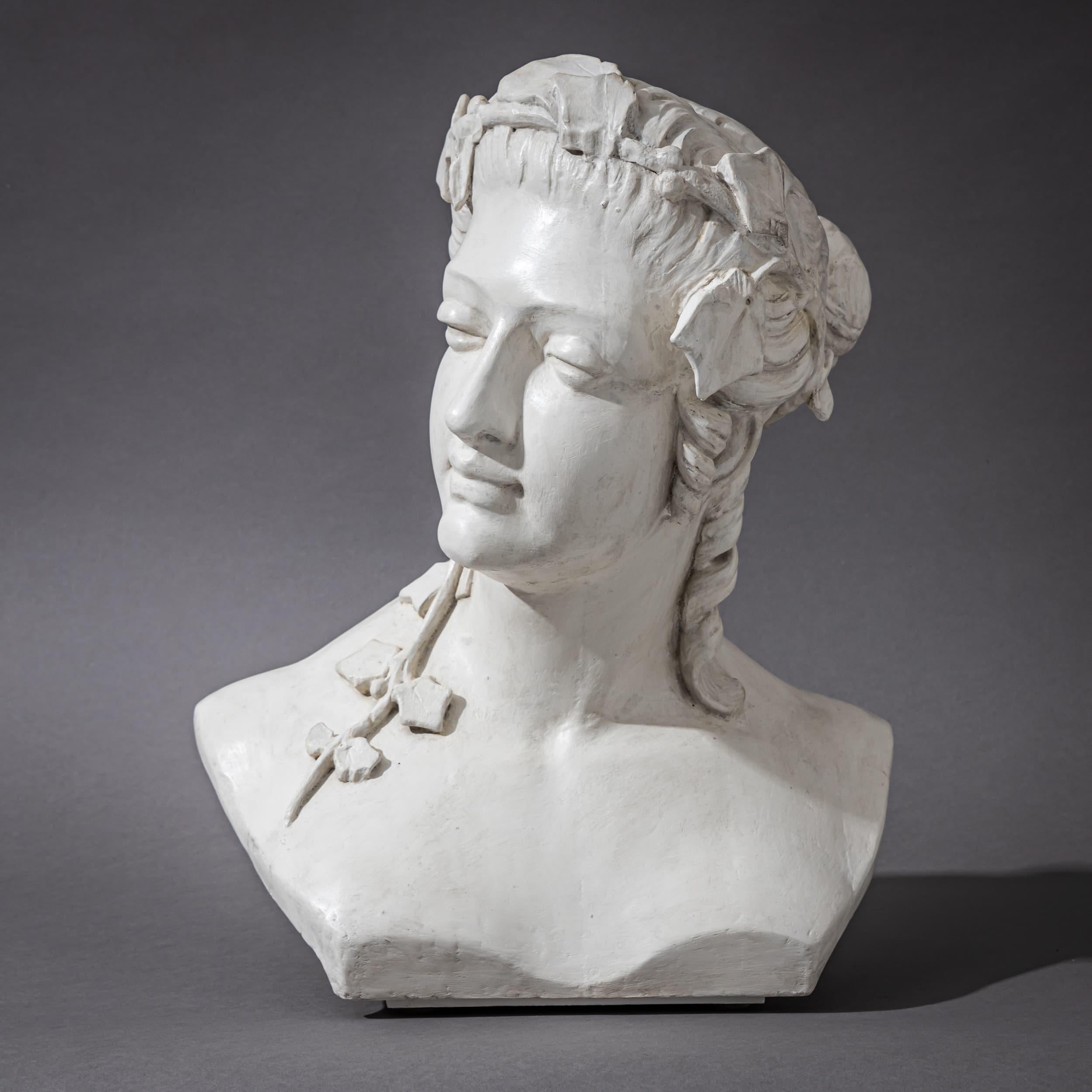 Expressive wood and plaster bust of a woman, crafted in the early 20th century in the Art Nouveau style. Her head is gently tilted to the side with a contemplative, distant gaze. Elaborately styled hair is adorned with a crown of intricately