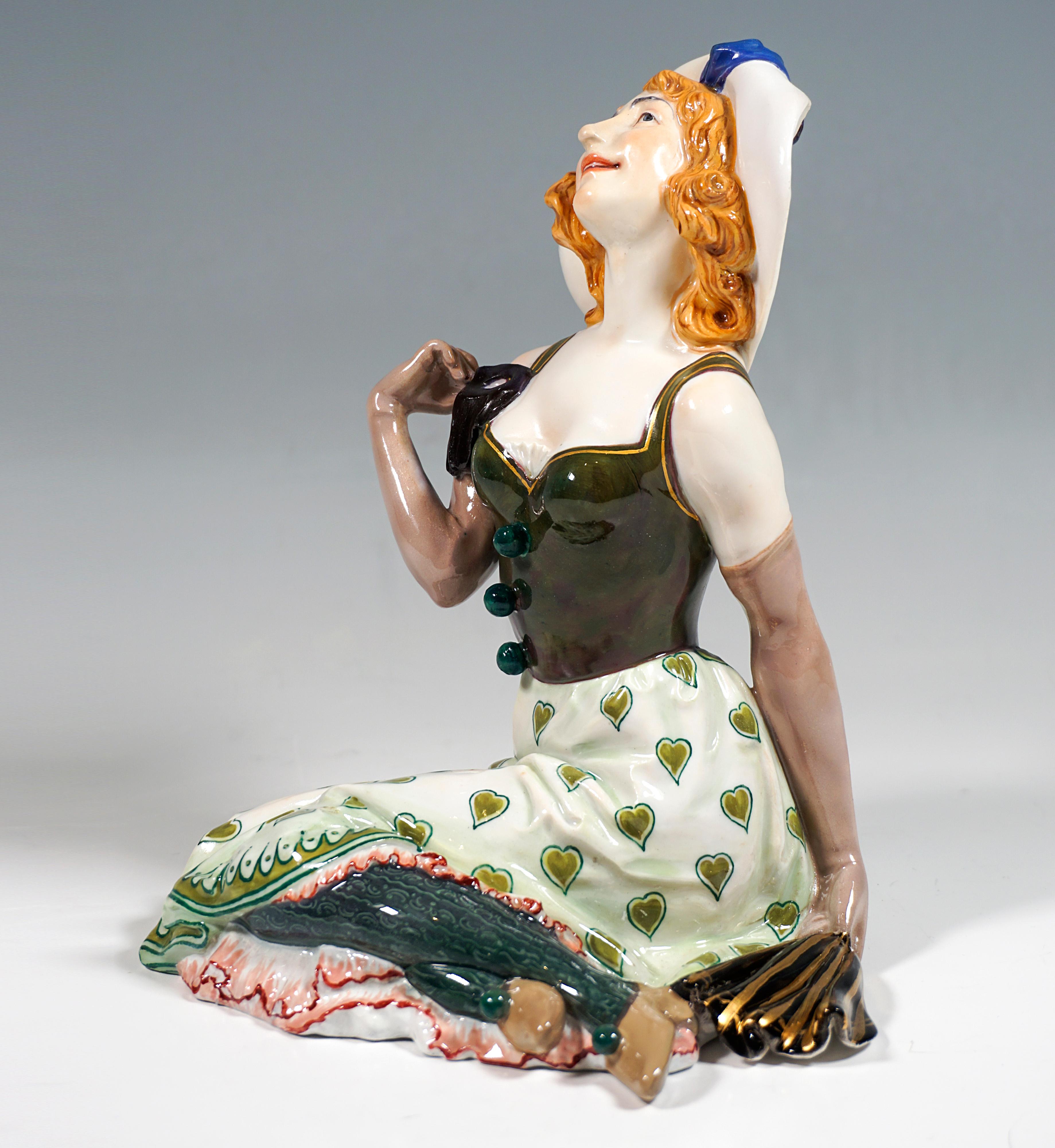 Extremely rare Meissen Art Nouveau porcelain figurine:
Red-haired girl sitting on the ground with big hat with brim turned up in front, dressed in green bodice with gold hem, wide skirt with green heart decoration and rosé petticoat, green woolen