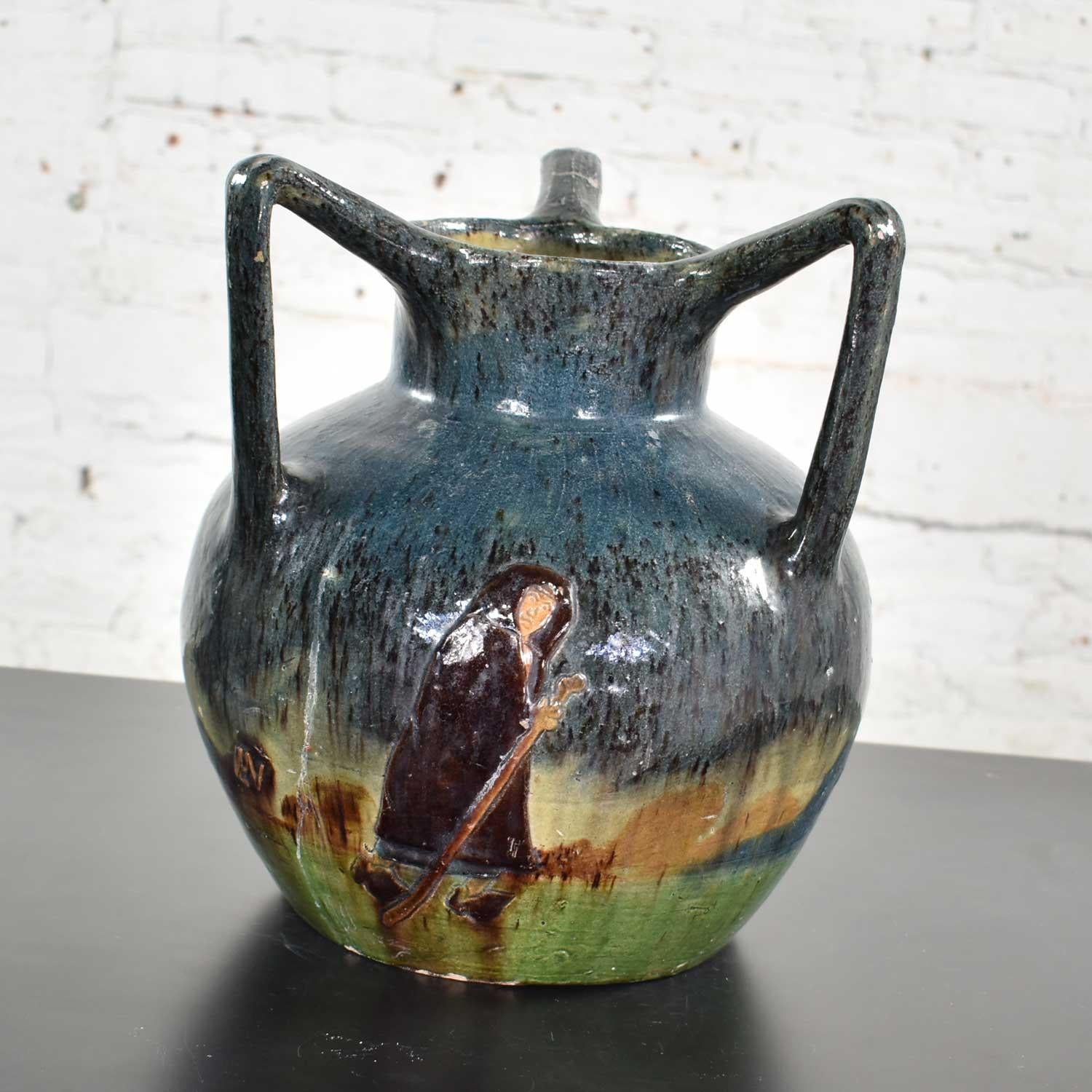 Handsome Art Nouveau Flemish earthenware three handled vase with applied L.M.V mark and decorated with figures in landscape. It is in good vintage condition. One handle has been restored and there are several glaze flakes and small chips; however,