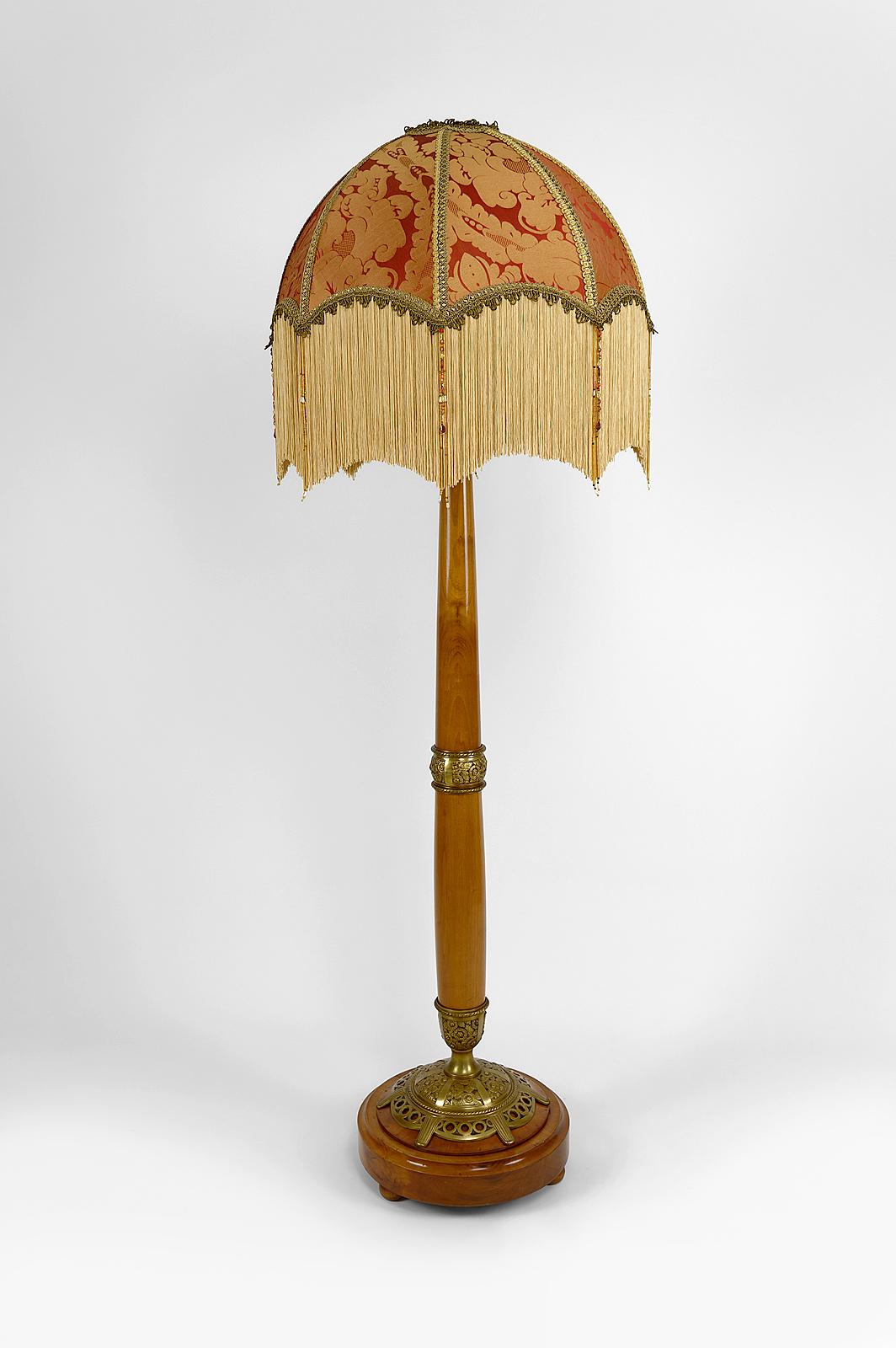 Superb floor lamp in blond cherry wood composed of a molded round base and a tapered shaft, enhanced with decorative elements in gilded bronze with stylized floral motifs.

The whole is mounted with a red and gold colored umbrella dome lampshade,