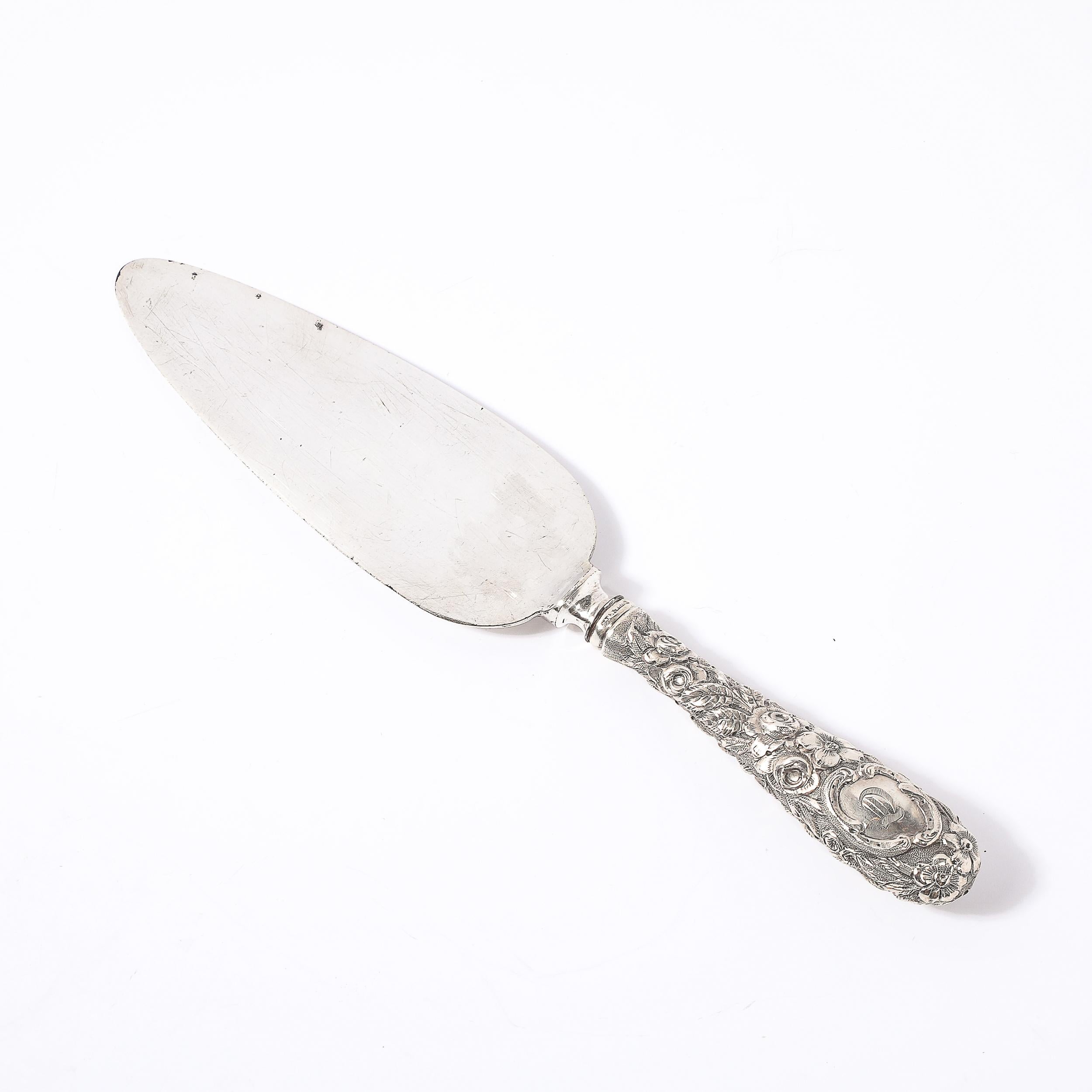 Dieser raffinierte Kuchenspender aus Sterlingsilber, der von der berühmten amerikanischen Silberschmiede Kirk-Stieff um 1910 hergestellt wurde, zeigt ein exquisites Jugendstil-Design, das die naturalistische Ästhetik dieser Zeit widerspiegelt. Der