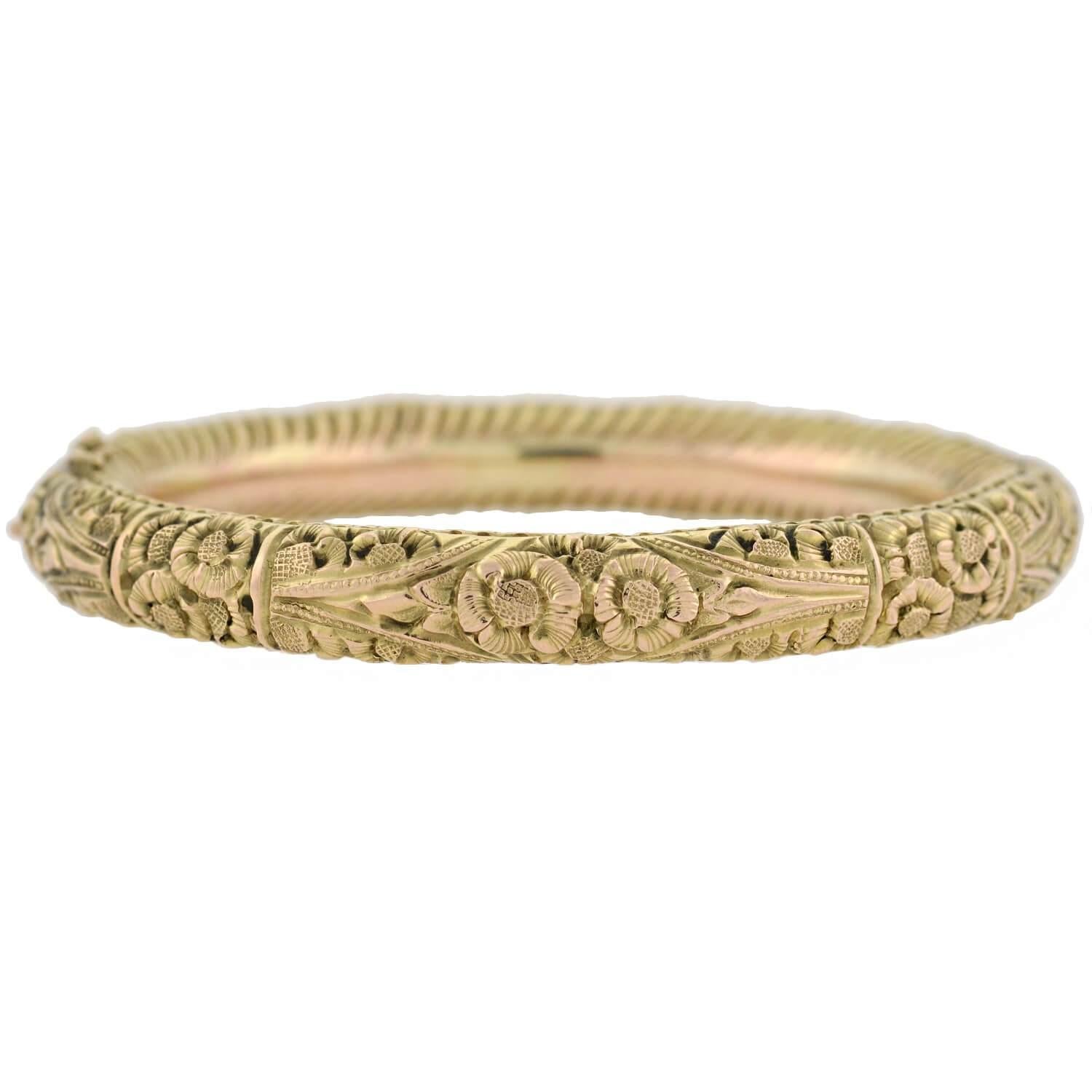 A gorgeous bangle bracelet from the Art Nouveau (ca1890) era! This decorative piece is crafted in 12kt yellow gold, and includes rose gold accents for a subtle mixed metals appearance. Covering the surface of the bangle is a carved floral motif,