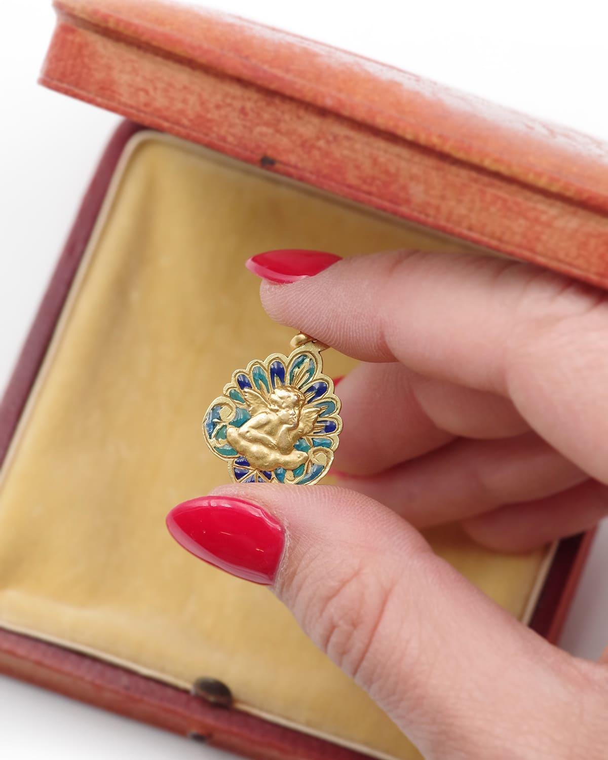 Art Nouveau Raphael angel medal in 18 karat gold. Antique baptism medal decorated with a cherub, the Angel of Raphael, in a plique-à-jour enamel frame in various shades of blue. It is so called because it is taken from the painting of the Sistine