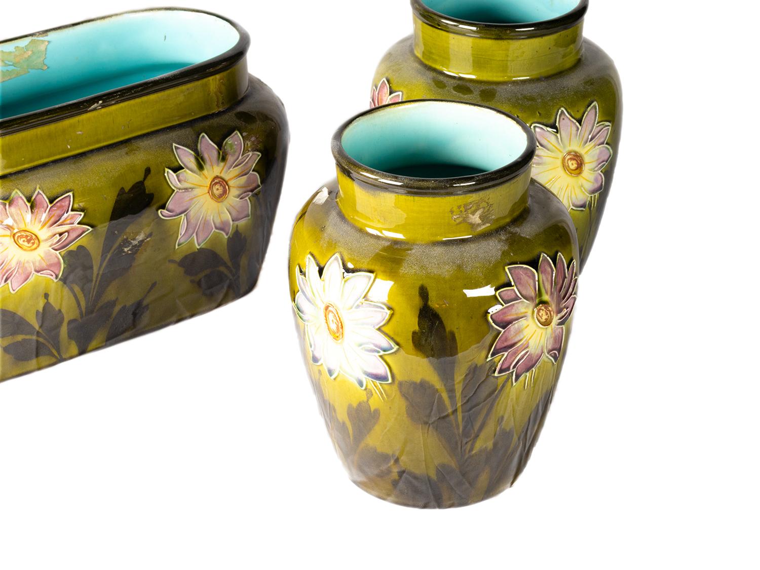 Ein dreiteiliges Set bestehend aus einem Übertopf und zwei Vasen aus olivgrüner Keramik, verziert mit Blumen im Barbotine-Stil, mit Interieur aus bläulich-grüner Keramik.
B FRANCE 50_2