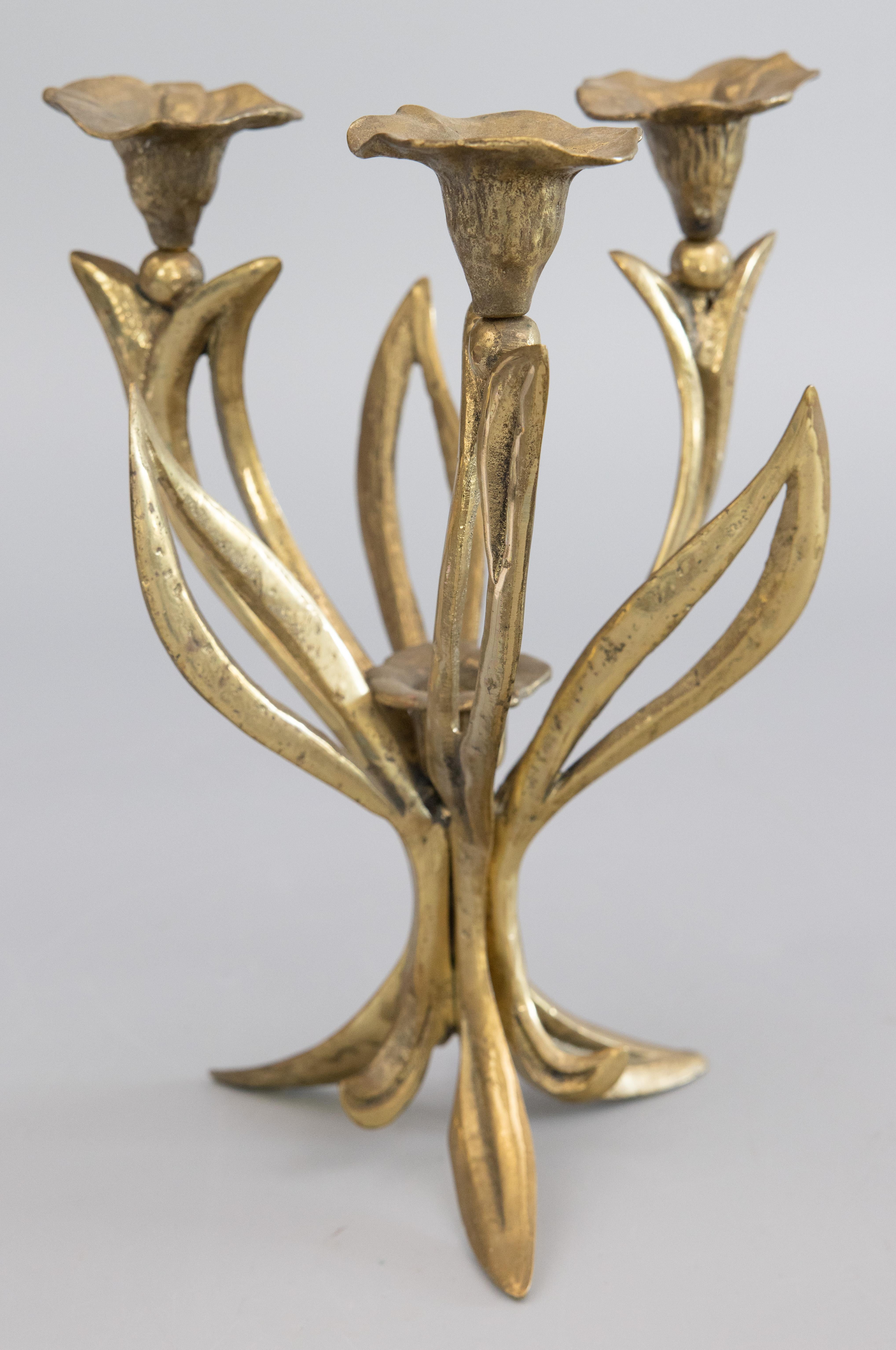 A gorgeous antique Art Nouveau French solid brass candelabra with four candle holders. This stylish candelabra is solid and heavy, weighing a substantial 3 lbs 10 oz, with a beautiful floral design depicting scrolling leaves and flower candle cups