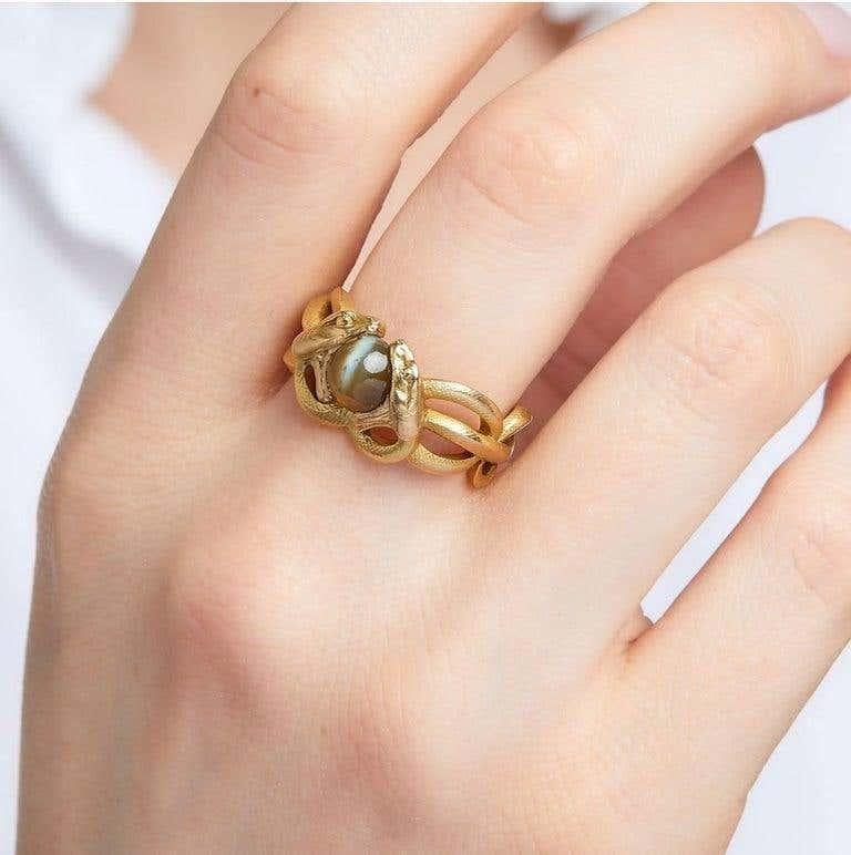 It represents two coiled snakes holding in their mouths a cabochon of chrysoberyl cat's eye. Yellow gold 18K mounting finely guilloched. 
Gross weight: 12.96 g. 
Finger size : 7 3/4
A chrysoberyl and 18K yellow gold snake ring, circa 1900. French
