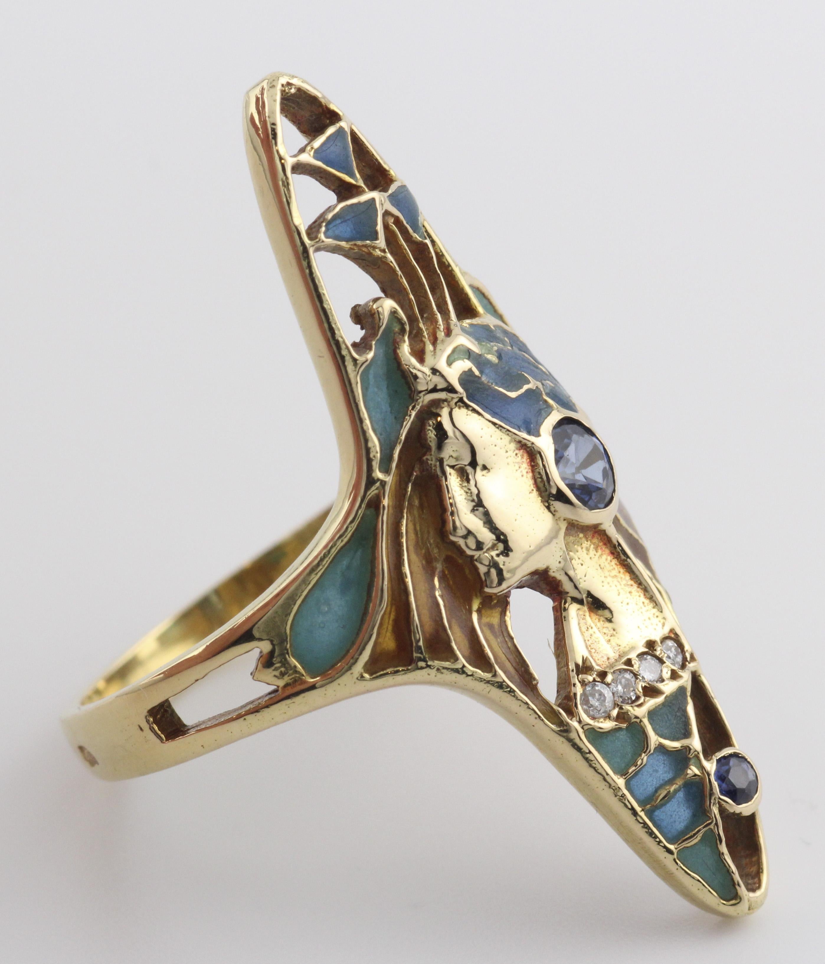 The Art Nouveau French Sapphire Diamond Enamel 18K Gold Ring is a magnificent and evocative piece of jewelry that embodies the exquisite artistry and enchanting aesthetic of the Art Nouveau movement. This ring features a stunning portrayal of a