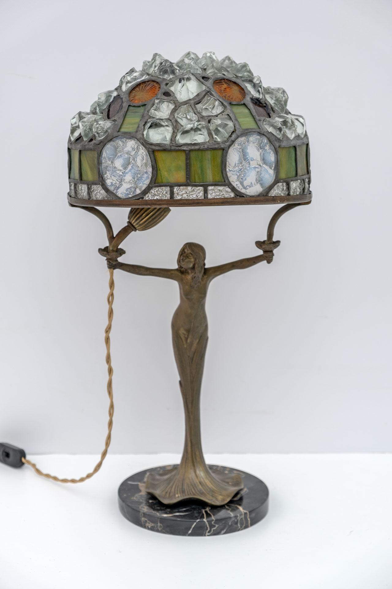 A beautiful Tiffany style table lamp, French production from the 1930s, Art Nouveau period. The base is in cast brass and base in black marble, the lampshade in colored glass and crystal pieces, leaded together. This lamp stands out from many others