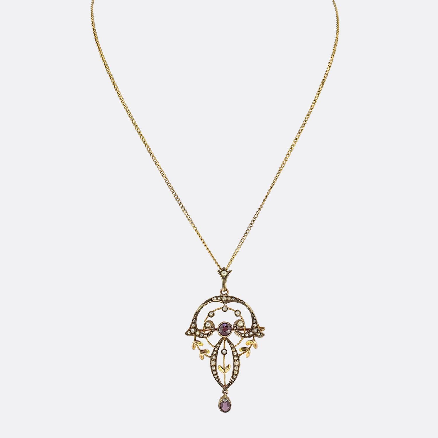 This is an antique Art Nouveau garnet and pearl pendant necklace. It has been set with a central garnet which is surrounded by multiple seed pearls along with an oval cut garnet drop in a 9ct yellow gold setting. The necklace has been suspended on a