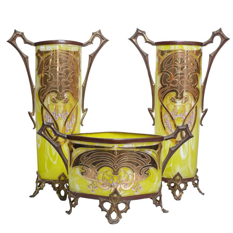 Art Nouveau Garniture
Materials: crystal and bronze with a golden patina and yellow crystals with white veins
Circa 1910 Origin: Czech Republic
It is composed of two glasses and a central planter
Excellent condition
no chips or