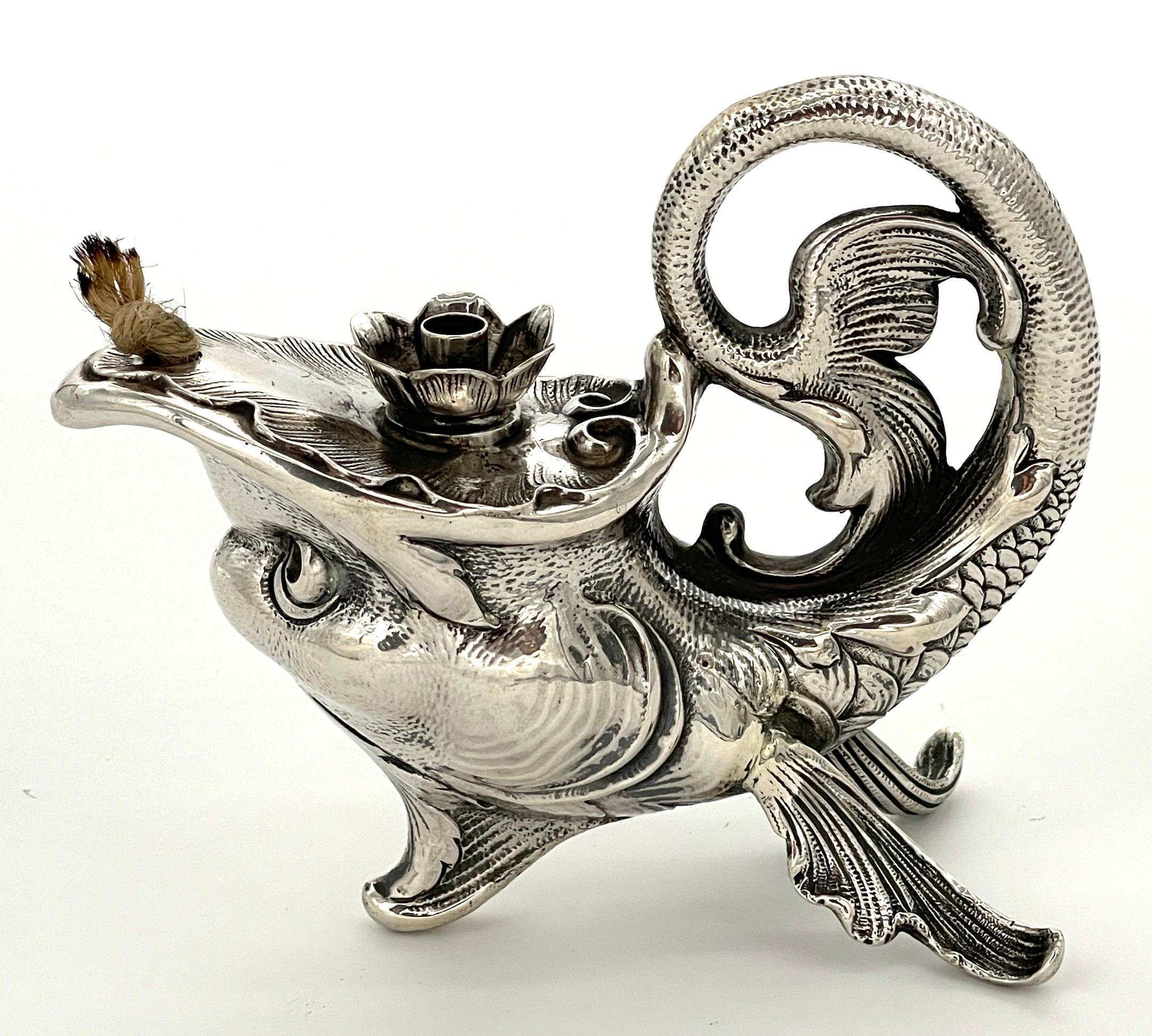 Art Nouveau German Sterling Fantasy Fish Motif Oil Lamp/Cigar Lighter
German, Late 19th Century, Unmarked, .800 Silver

Immerse yourself in the enchanting world of Art Nouveau with this captivating German sterling fantasy fish motif oil lamp/cigar