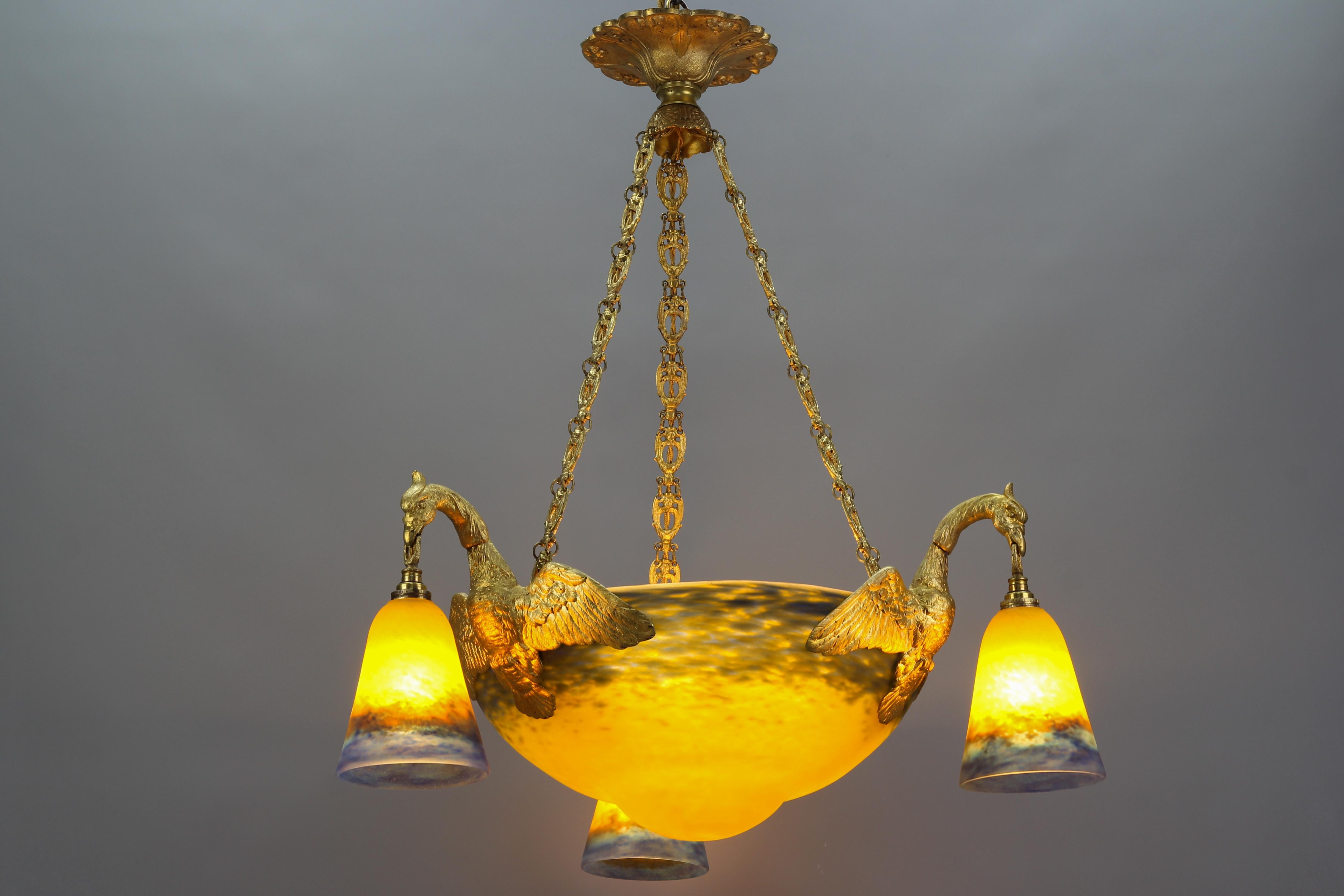 French Art Nouveau gilt bronze and Muller Frères Lunéville glass six-light chandelier, circa 1920.
This impressive French Art Nouveau period chandelier features a mottled “Pâte de Verre” central, beautifully shaped glass bowl in yellow and blue