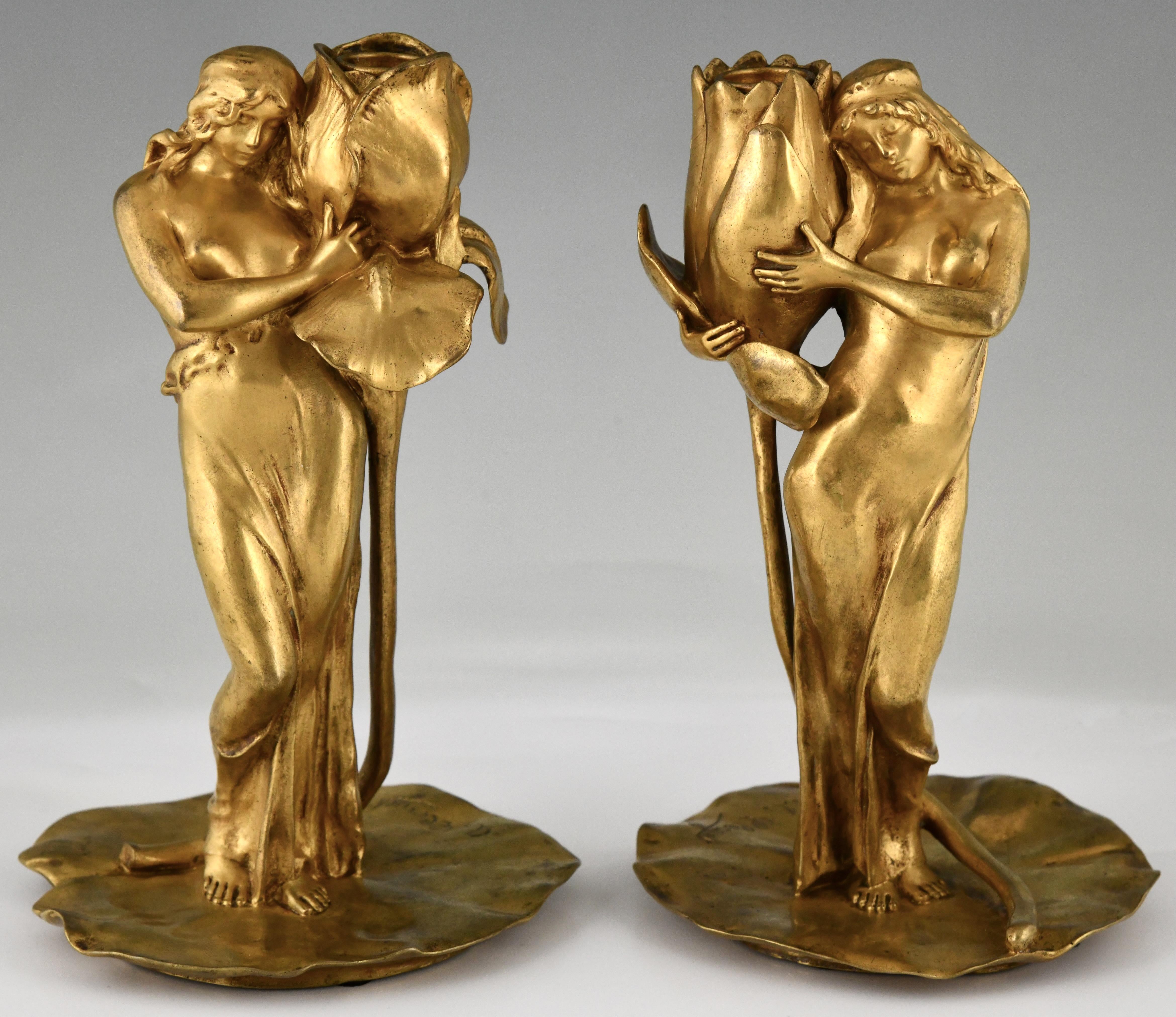 Pair of Art Nouveau gilt bronze candlesticks lady with flower Iris and Lotus by Alexandre Clerget.
Siot Decauville Paris foundry mark. 
France 1900. 
This pair is illustrated on page 115 of the book  Dynamic Beauty,  Macklowe Gallery  and in