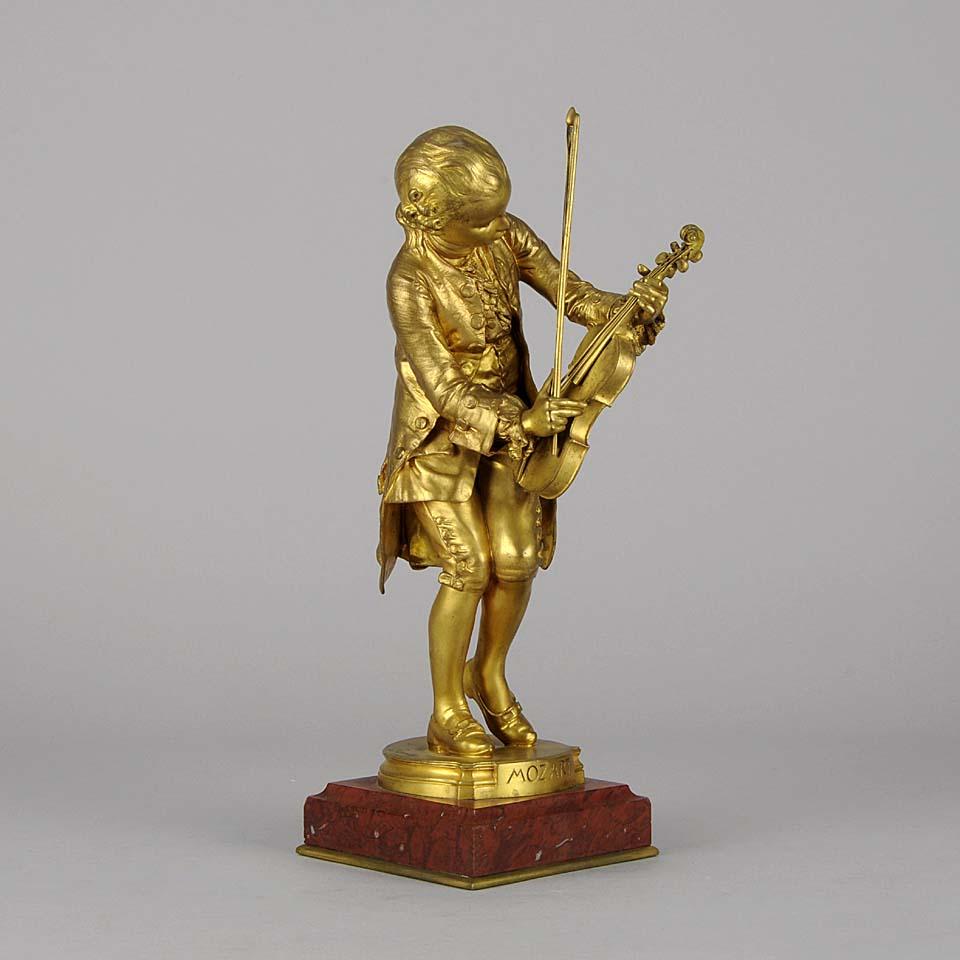 An exquisite early 20th century gilt bronze study of the famous composer ‘Mozart’ tuning his violin, dressed in period attire. The bronze surface with excellent hand finished detail and fabulous color, signed Barrias, inscribed F Barbedienne Fondeur.
