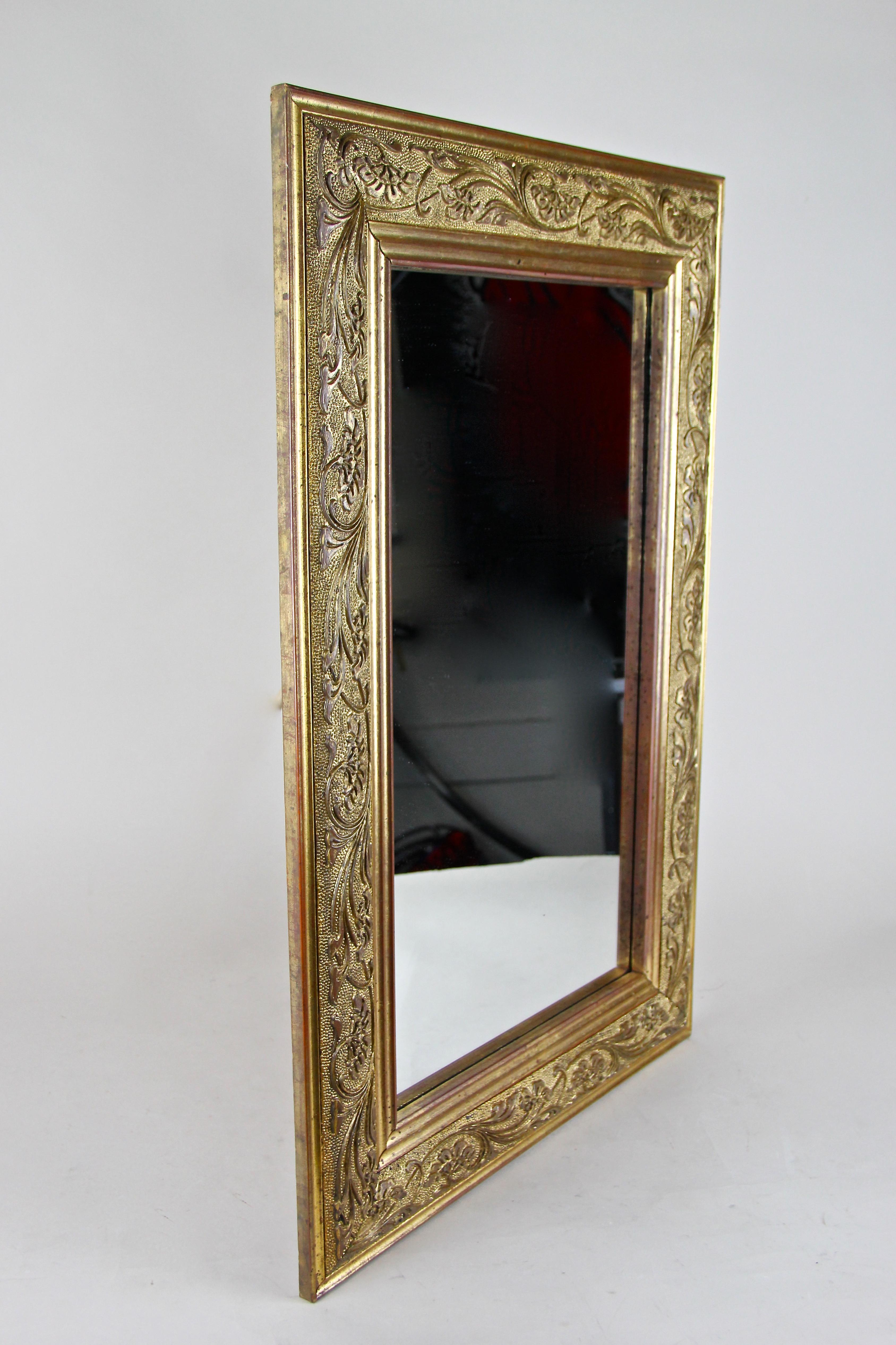 Enchanting golden Art Nouveau wall mirror from the era in Austria around 1900 This mirror impresses with a beautiful designed frame covered with composition gold and adorned by a fantastic stucco work showing delicate flower ranks, an epitome of the