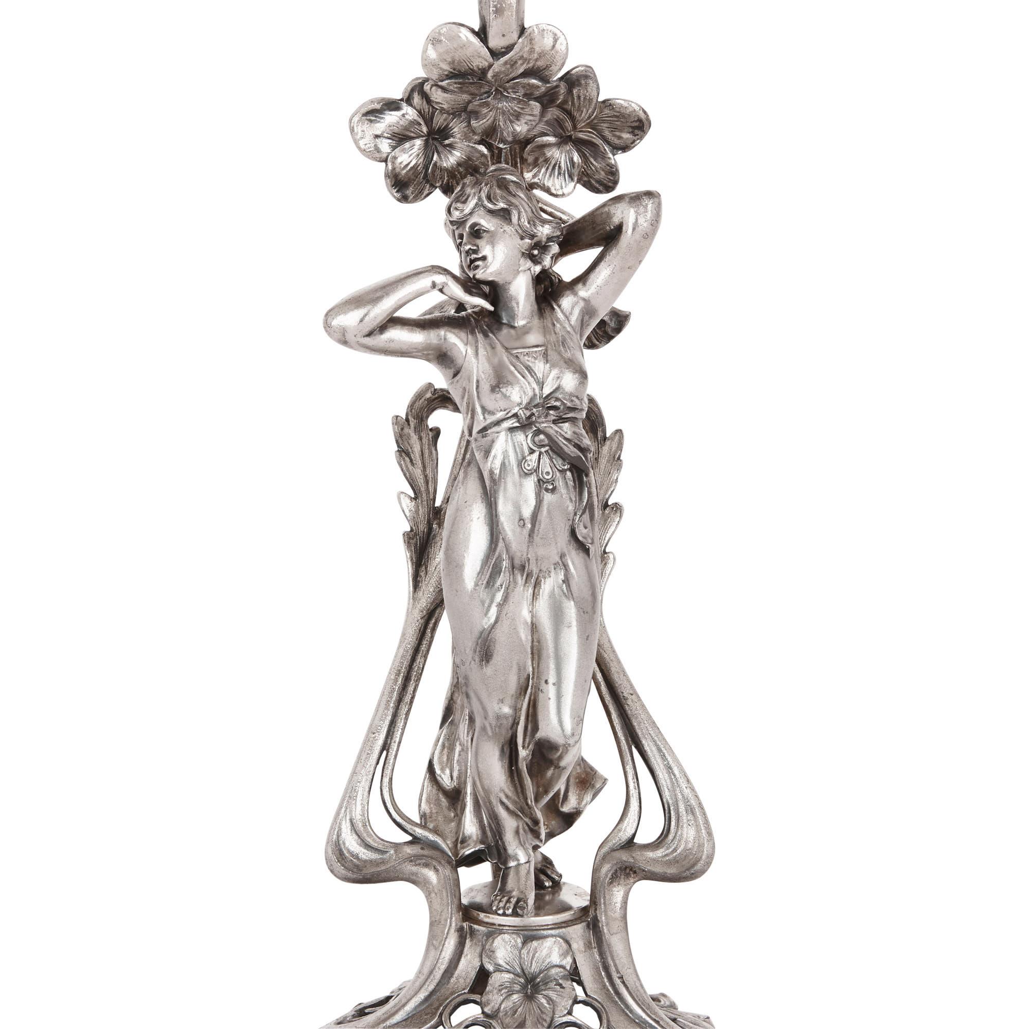 This graceful centrepiece was created in the early 20th century by the German company, Württembergische Metallwarenfabrik (WMF). WMF was a prestigious factory which produced metal Jugendstil or Art Nouveau style decorative art. This beautiful