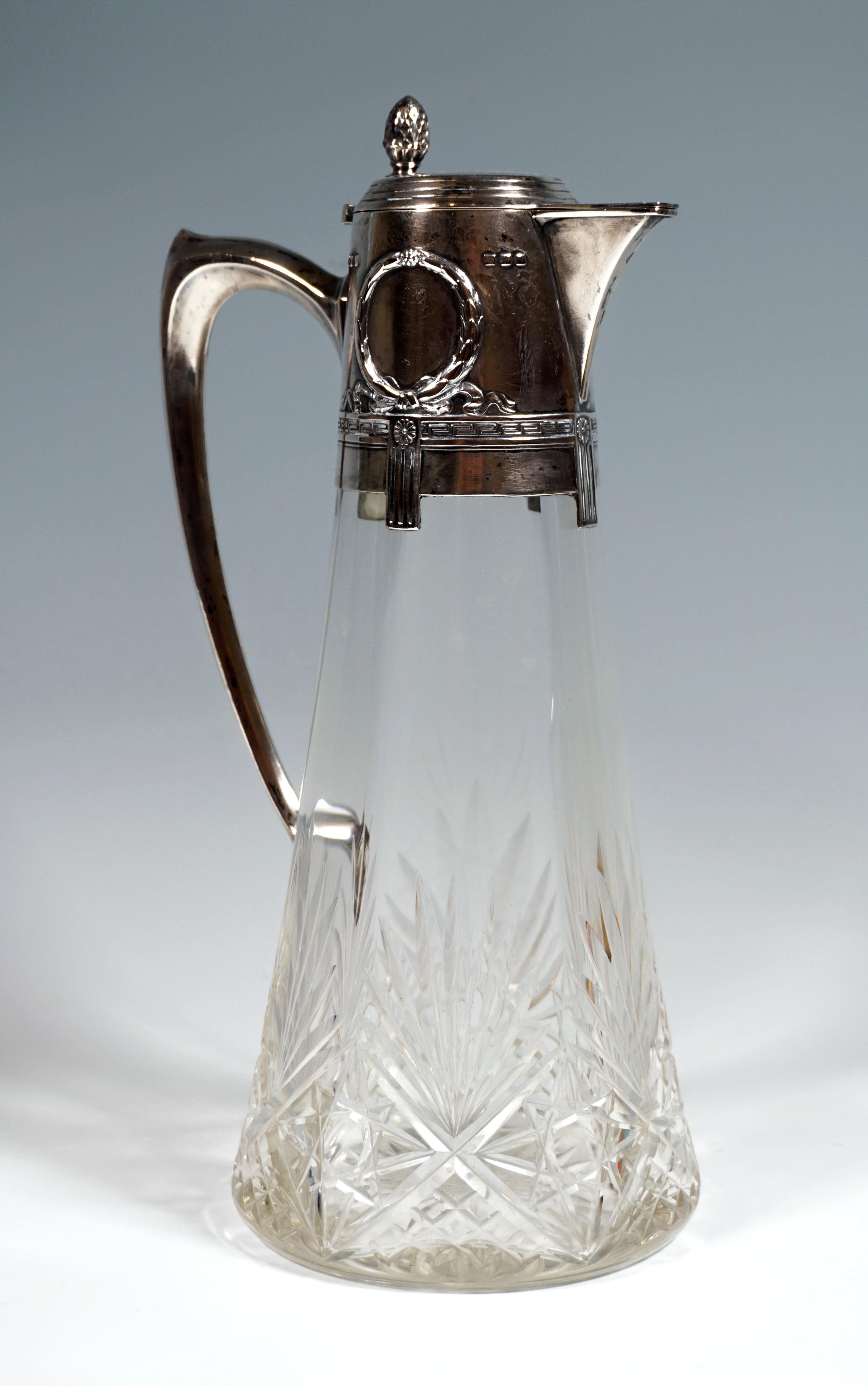 Carafe en verre transparent à corps conique, paroi intérieure épaissie en forme de vague à six branches, découpée près de la base avec un décor d'étoiles et de poutres, étoile au sol, garniture en argent avec un décor de couronnes et de nœuds, ruban