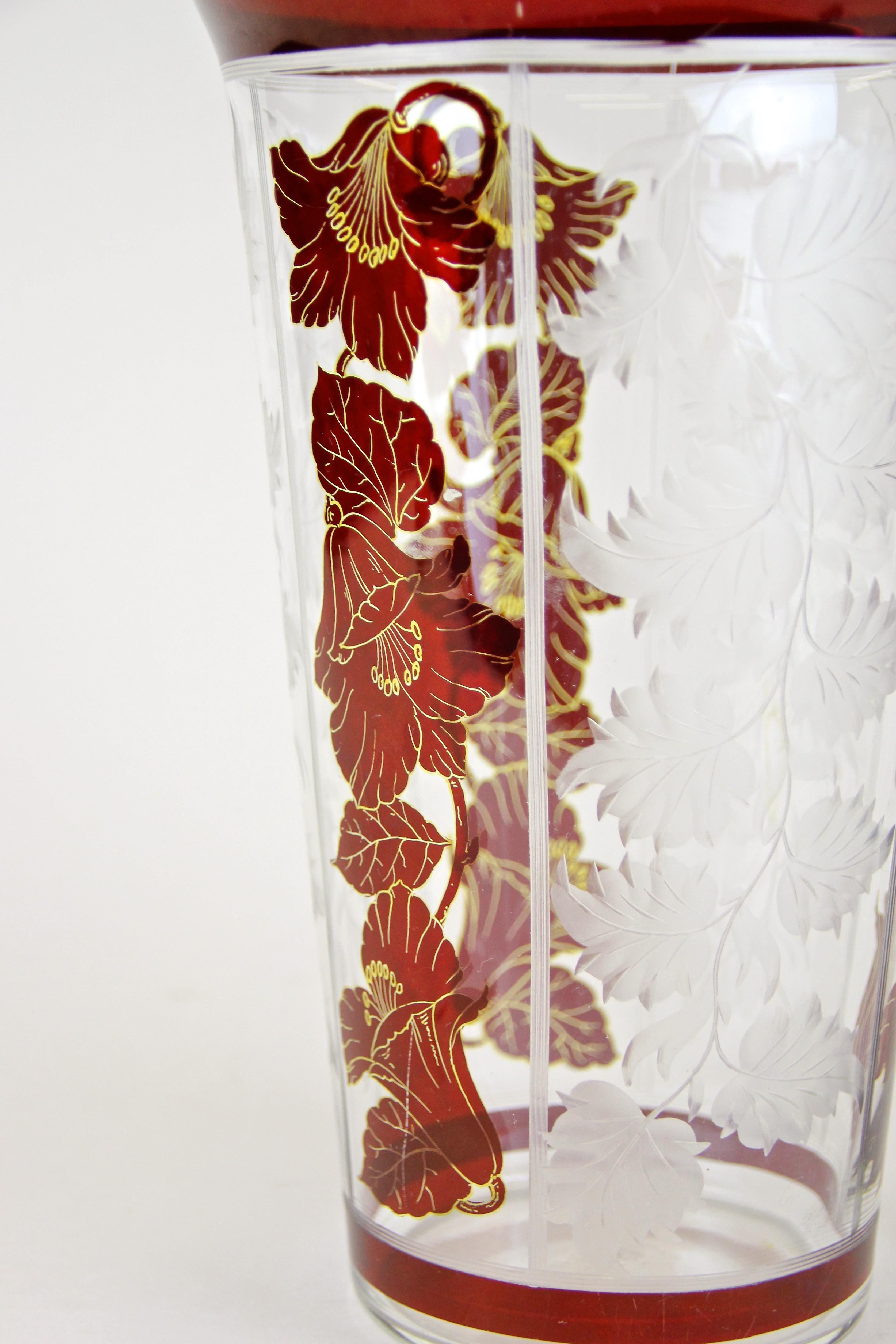 Charming Art Nouveau glass vase with flowers and engraved leaves from the early period in Austria, circa 1900. The artfully designed vase enchants with lovely dark red flower prints adorned by golden accents and extraordinary engraved leaves,