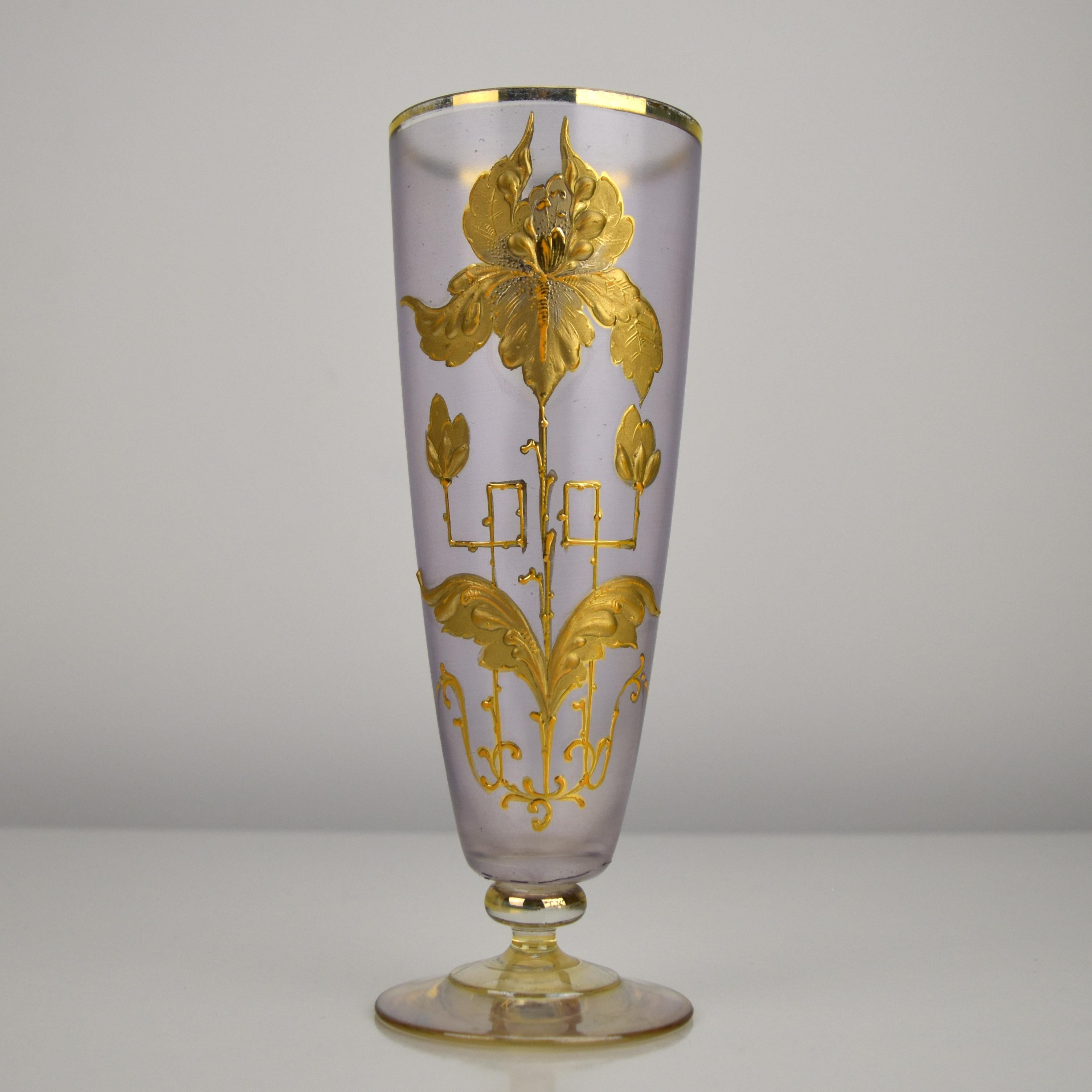 This beautiful Art Nouveau glass vase features a delicate violet-stained satin finish, showcasing its refined craftsmanship. A stylized iris motif in raised relief enamel, adorned in radiant gold, gracefully enhances the surface, epitomizing the