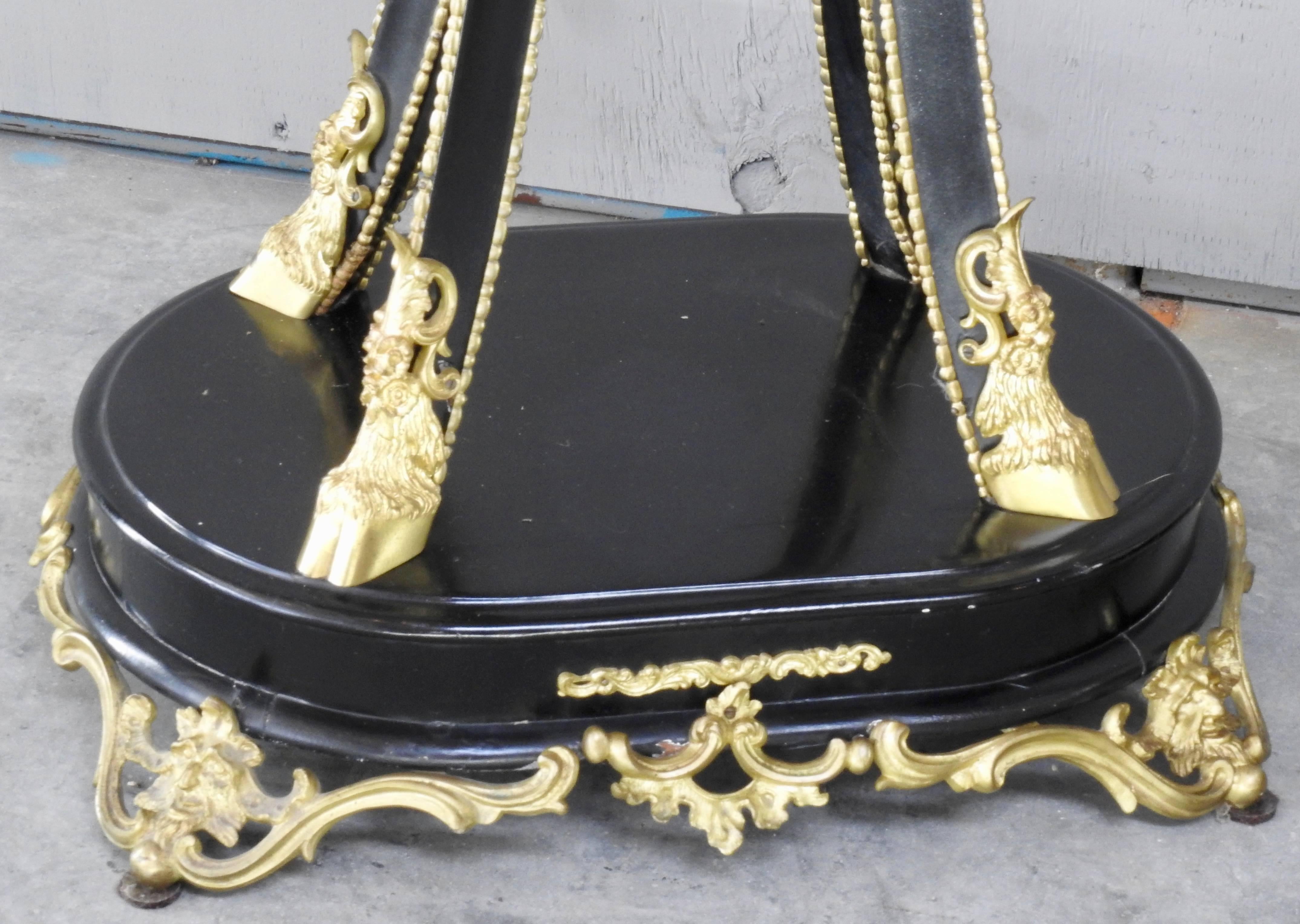Featured are an elaborate pair of black enameled goat feet pedestals from the late 19th century. The feet are gilded bronze as well as the other ornate metal trim pieces. The goat heads appear near the top of the pedestal. The black enamel was