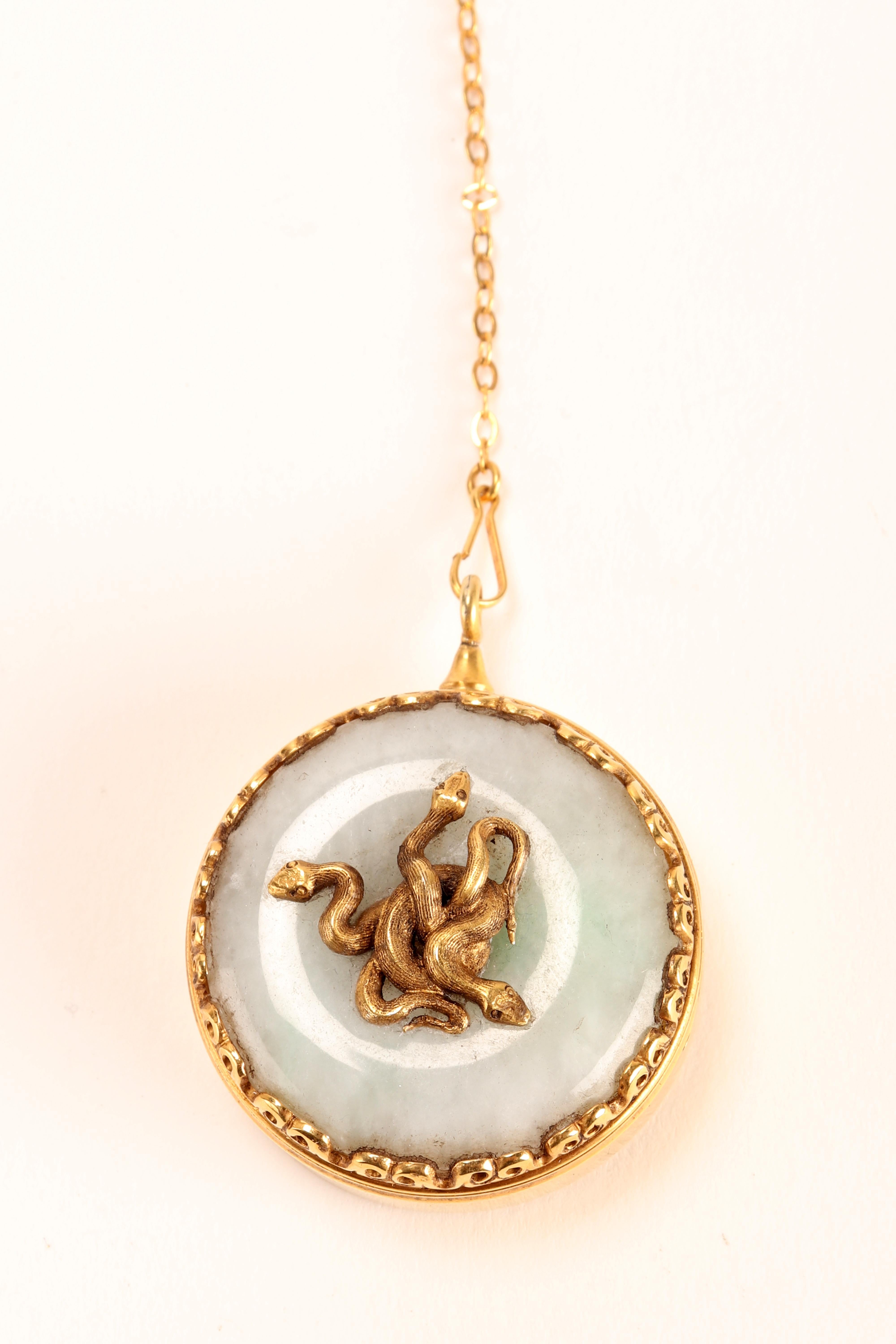 Round Art nouveau Vinaigrette, made of 18K gold. Configured as a pendant with safety lock.The lid of the box is in white jade with in the center several coiled snakes that also invade the inside of the lid. Marks: eagle head and goldsmith's mark