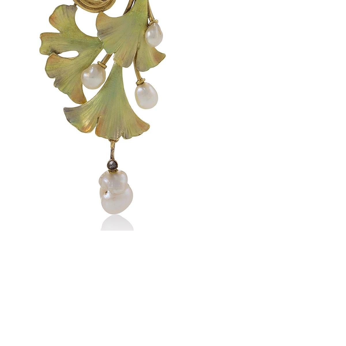 A French Art Nouveau 18 karat gold, enamel and diamond ginkgo leaf pendant, centering an oval pearl within a surround of ridged swirling vines, suspending a cascade of leaves and buds in iridescent green enamel with orange tones, accented by an old