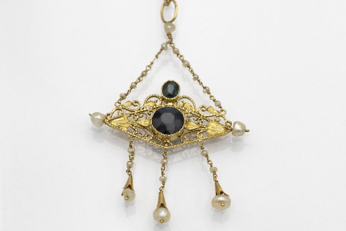 Collana antica in oro 14 carati con zaffiri e perle. La collana ha due zaffiri blu scuro sfaccettati del peso di circa 2,50 carati. Inoltre, è tempestato di 21 perle naturali di forma irregolare.

Catena in oro 14 carati, lunga 41 cm.

Dimensioni
