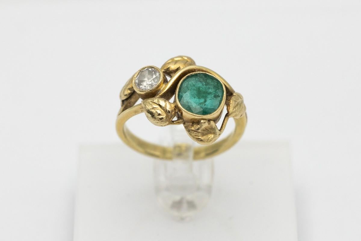 Antique Art Nouveau ring made of 14 carat yellow gold. It comes from Vienna around 1910. Ring set with an oval, facet-cut emerald, weight approx. 1,20 ct. and a diamond in an old cut diamond weighing approx. 0.50 ct. Ring made in the shape of a vine