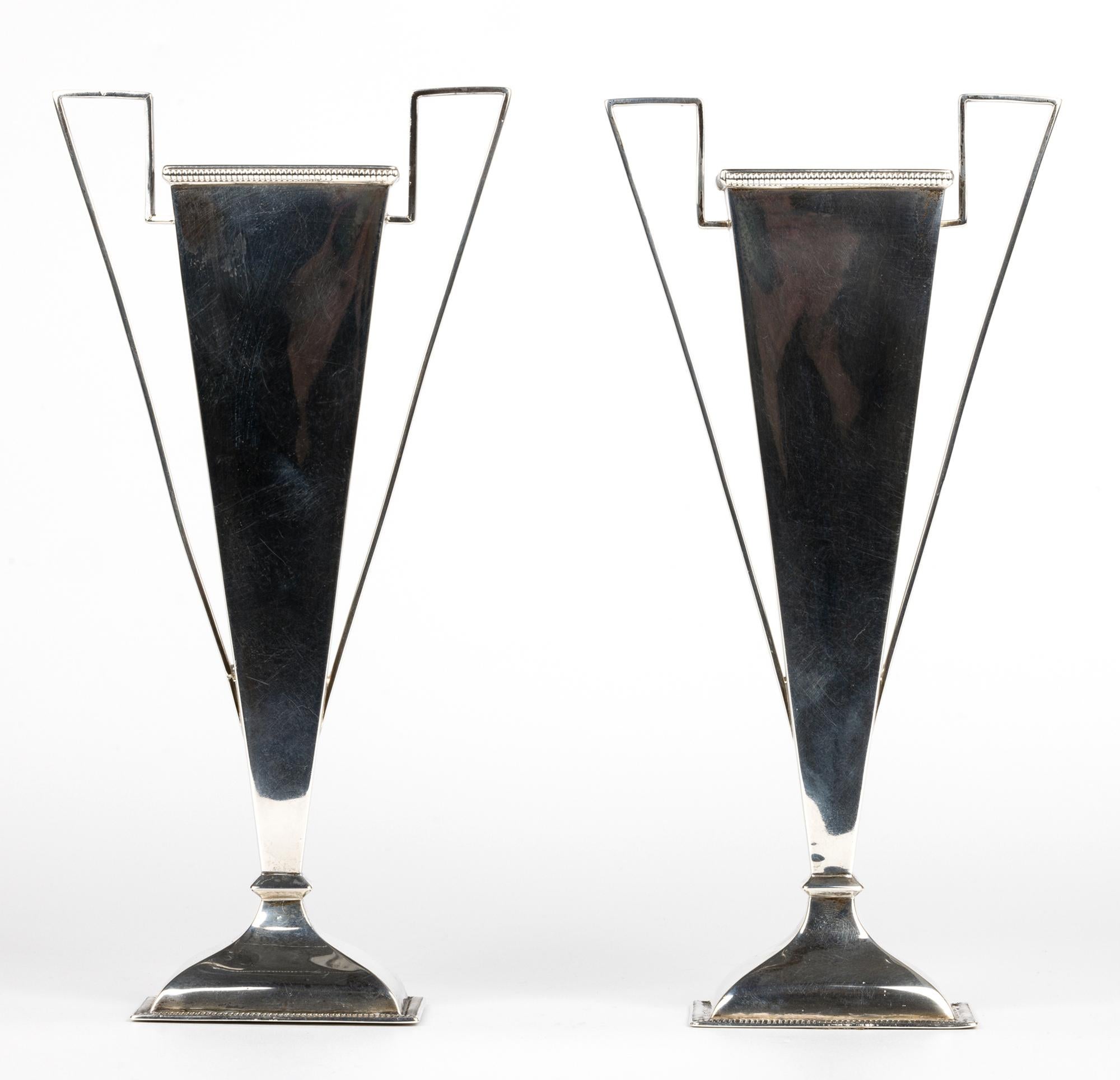 Una coppia di candelieri in argento con due manici, molto eleganti e di qualità, realizzati dai rinomati argentieri londinesi Goldsmiths & Silversmiths e risalenti al 1909. Questi vasi dalla forma semplice ed elegante poggiano su una base