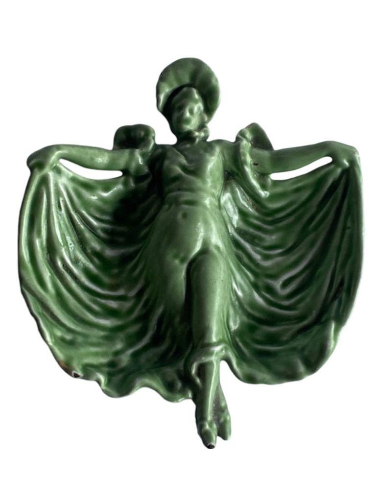 This Art Nouveau ring/candy dish by Pemco, showcases the elegance of the Edwardian era with its cast iron construction and light green/teal color palette. Featuring a depiction of a dancing woman, it exudes the graceful style of Art Nouveau. The
