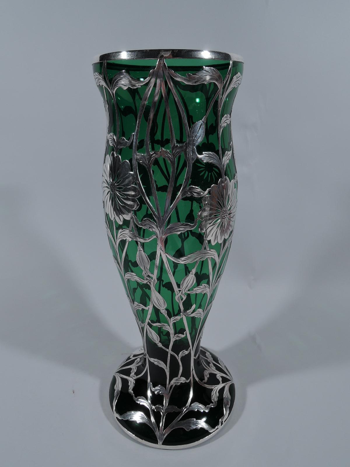 Turn-of-the-century Art Nouveau green glass vase with engraved silver overlay. Made by Matthews (later Hickok-Matthews) in Newark. Tall and full baluster flowing into spread round foot. Vertical overlay pattern comprising stems flowers and tendrils.