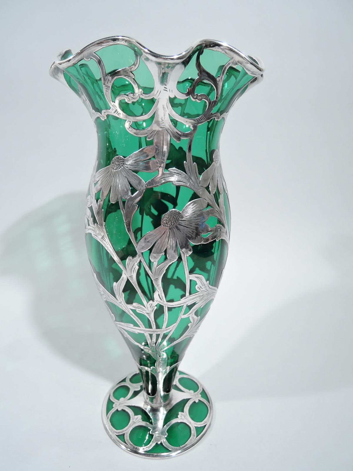 Turn-of-the-century American Art Nouveau glass vase with engraved silver overlay. Ovoid body with flared and ruffled rim and round flat foot. Overlay in form of daisies with entwined stems and leaves, and missing petals evocative of the age-old