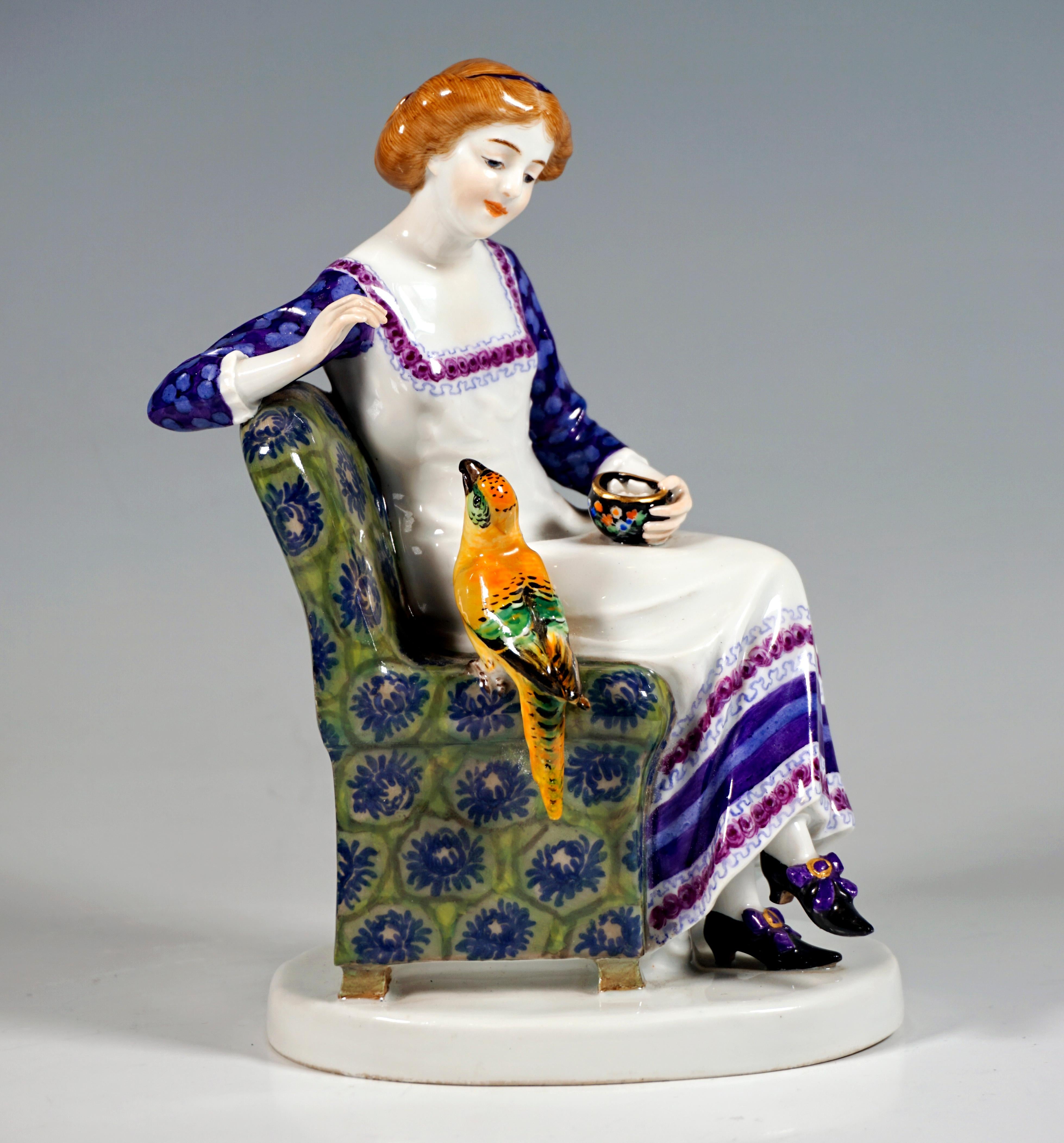 Very rare Meissen Art Nouveau porcelain group:
Young lady with her hair pinned up, in a white dress with embroidered borders over a flowered blouse, sitting cross-legged on an armchair upholstered with elaborate Art Nouveau fabric and feeding a