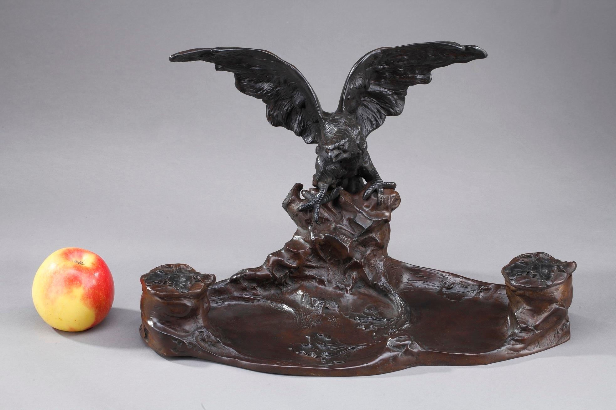 Late 19th century Art Nouveau inkwell and tidy crafted of bronze with brown and black patina, featuring an eagle with spread wings on a rock. This desktop piece includes two containers for ink hidden in the naturalist landscape. Signed on the base A