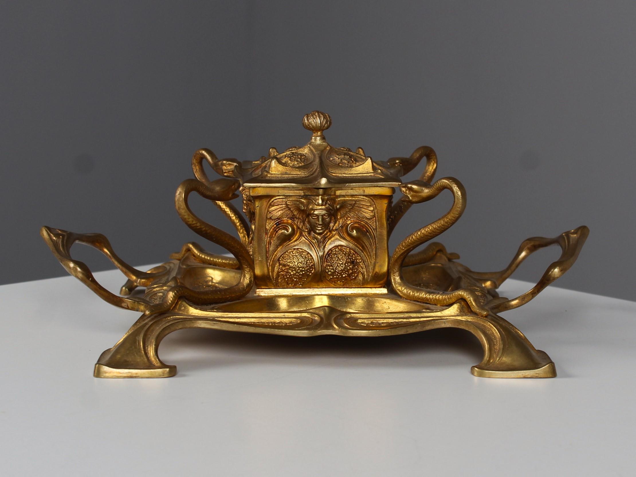 Exceptional Art Nouveau Inkwell from France, 1900- 1920s.
The square inkwell in the center is guarded by four snakes at each of its corners. The lid, made of curved Art Nouveau ornaments, reveals the original glass inkpot when opened.
On each side