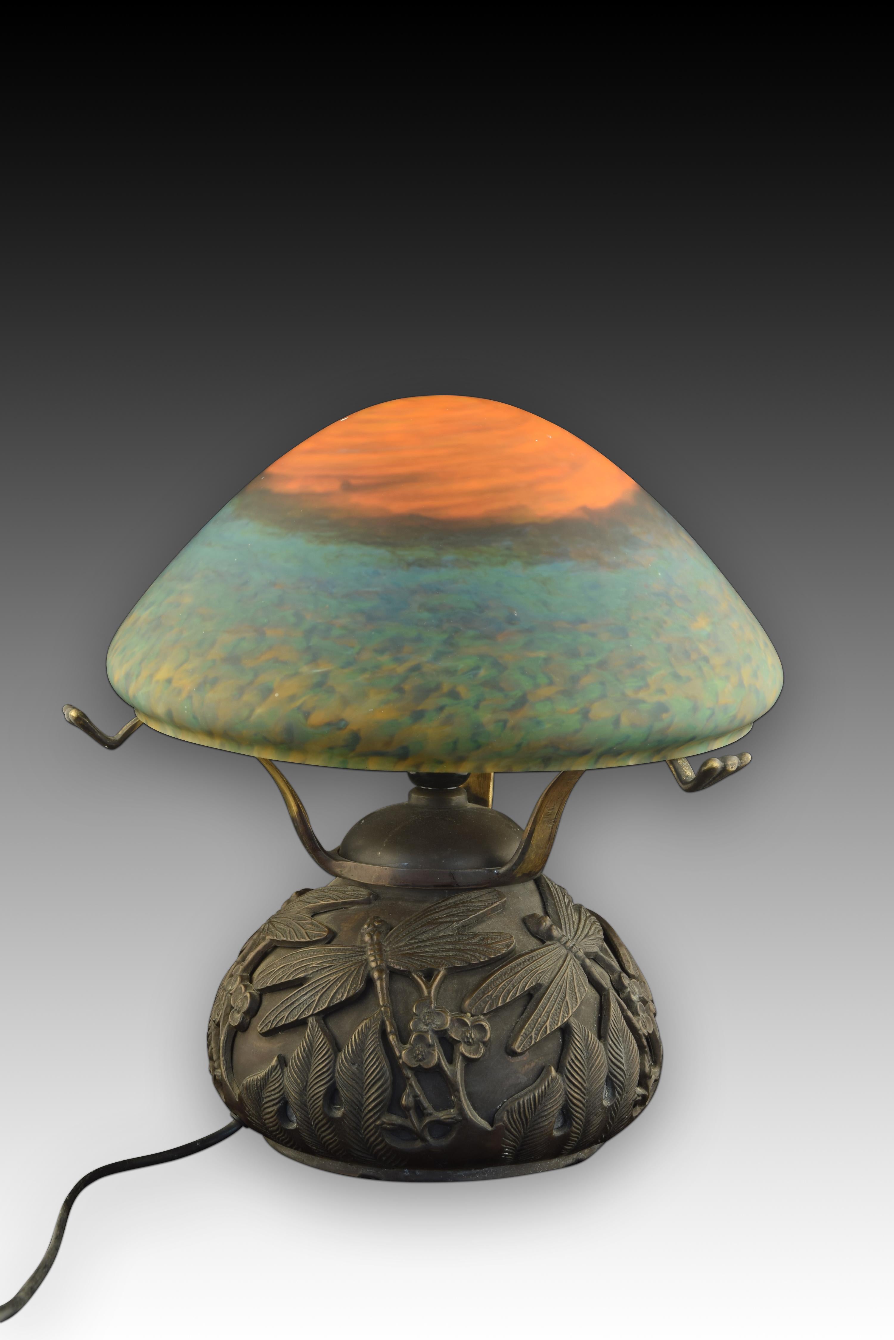 Art Nouveau style table lamp. Bronze, glass. 
Table lamp with a bronze base decorated with dragonflies, leaves, flowers, etc., clearly inspired by Art Nouveau pieces. The lampshade is made of glass, and has various colors. 
Weight: 8.1 kg. Size: