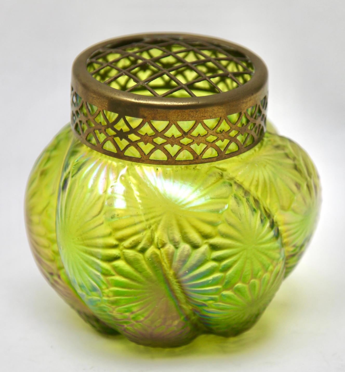 Art Nouveau iridescent glass Pique Fleurs' vase by Loetz' with Grille

Subtle, hand blown glass vase in the Art Deco style. This design for vases is often called 'Pique fleurs' or 'rose-bowl' and is supplied with a fitted metal grille to support