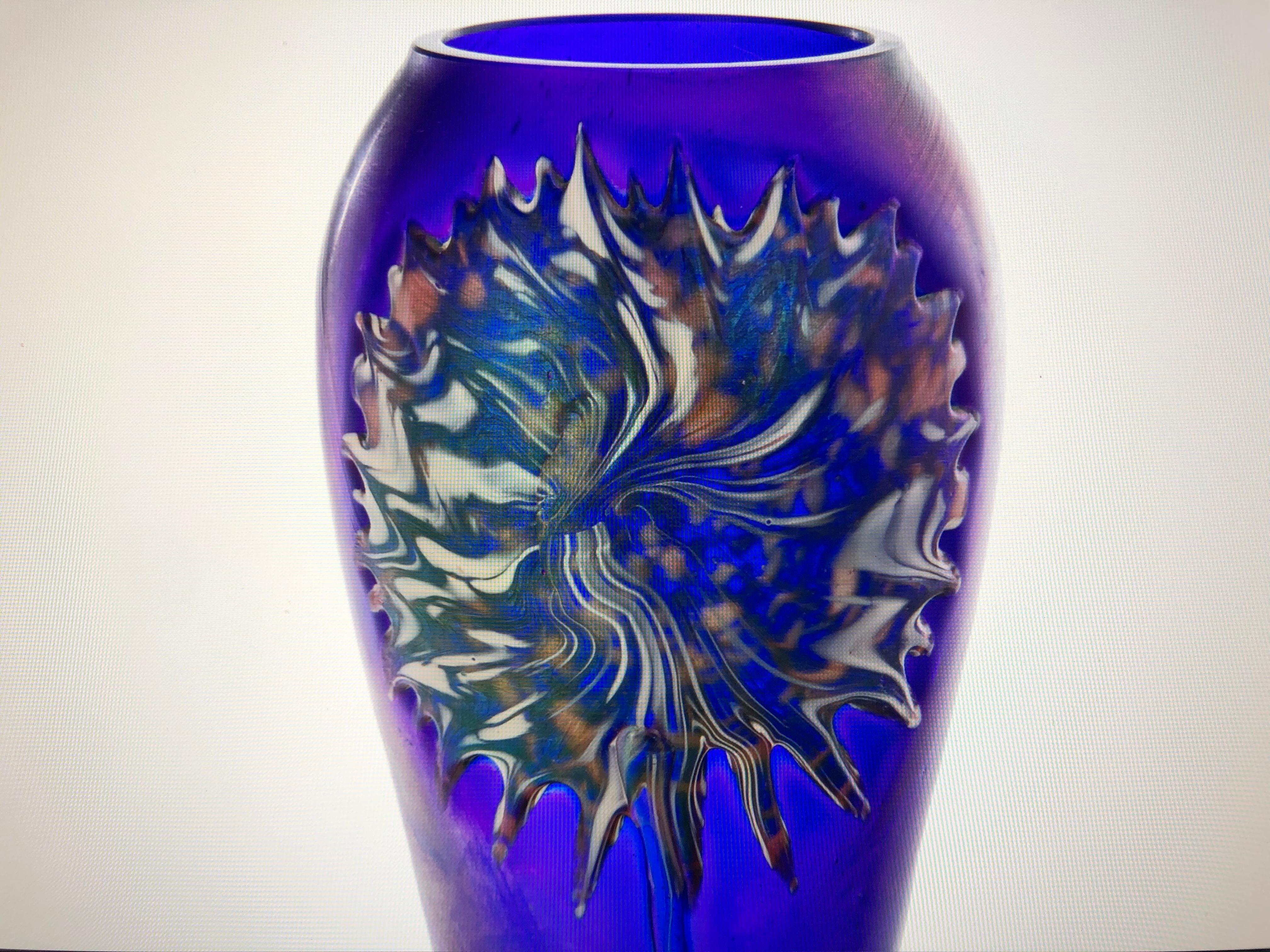 A stunning, irisdescent, purple baluster form vase with a stylized floral bloom in green and orange. Attributed to Quezal, early 20th Century. In perfect condition.
The Quezal Art Glass and Decorating Company began in New York in 1901 under the