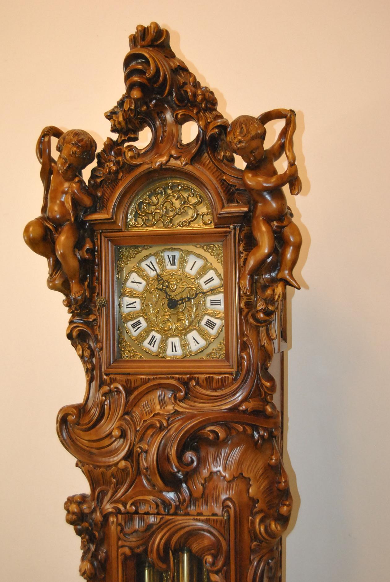 At Nouveau Italian Baroque walnut grandfather clock with caved cherubs. Brass dial has porcelain markers. Eight day Franz Hermle chain wound movement. Running condition. Chimes every quarter and on the hour.