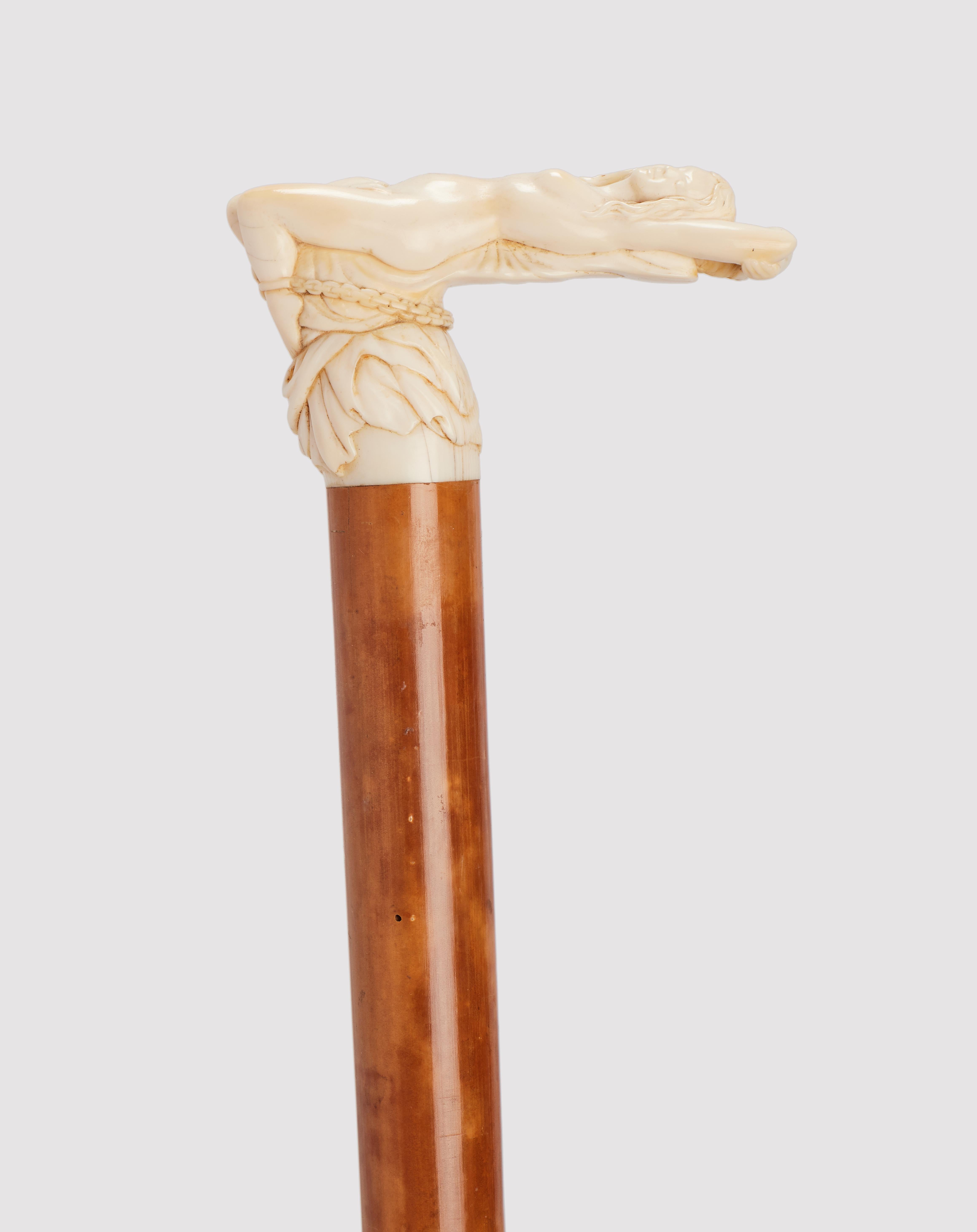 Canne : Manche en ivoire sculpté, représentant la scène de la mith grecque d'Andromède enchaînée aux rochers. Poignée en forme de L. Arbre en bois de Malacca. Virole en métal. Angleterre vers 1880. (LIVRAISON DANS L'UE UNIQUEMENT)