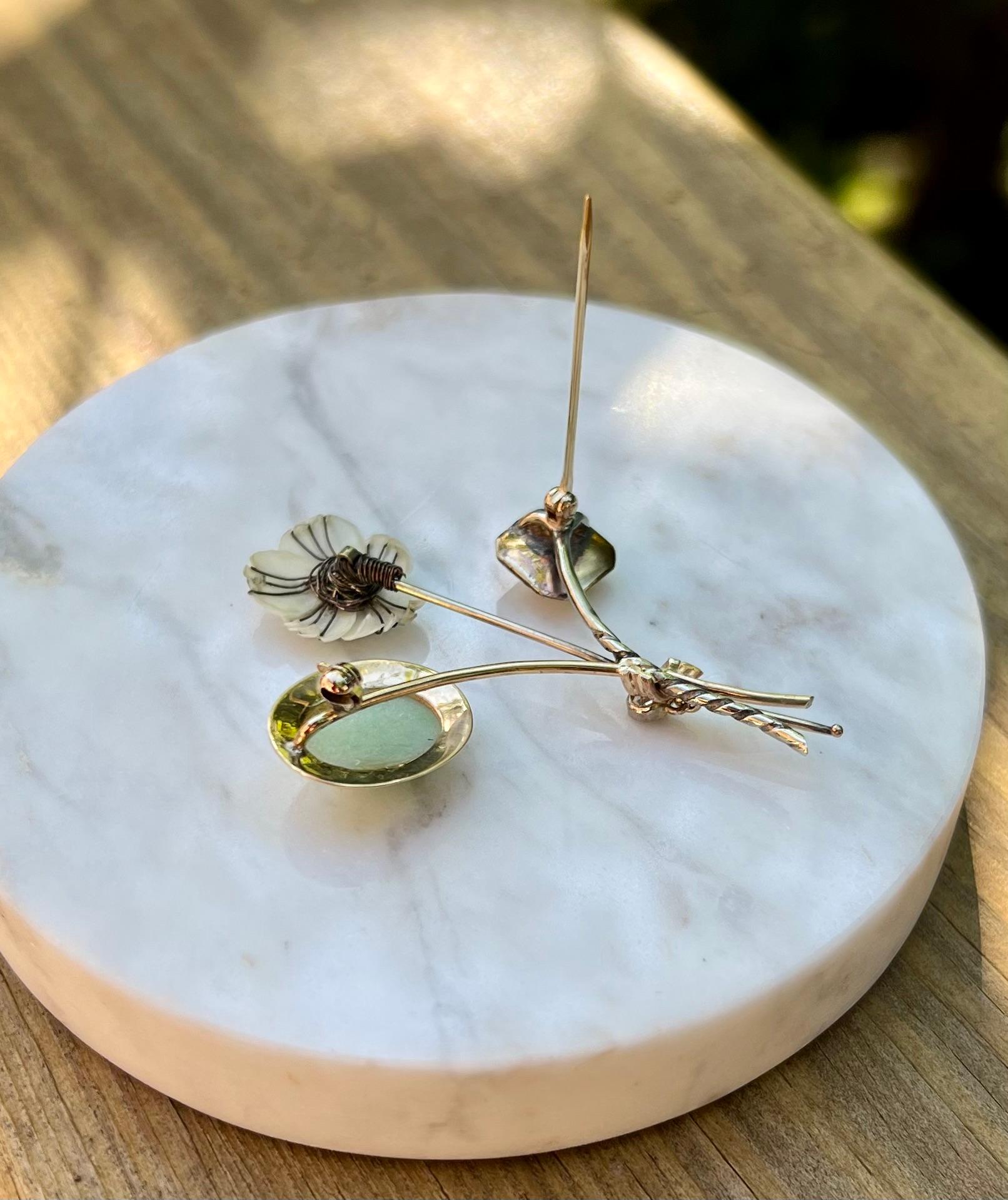 One 14 karat yellow gold (stamped 14K) and sterling silver pin set with one oval jade stone, two cultured pearls, shell, and one rose-cut diamond, approximately 0.10-carat total weight with I/J color and I1 clarity.  The pin measures 2 inches long