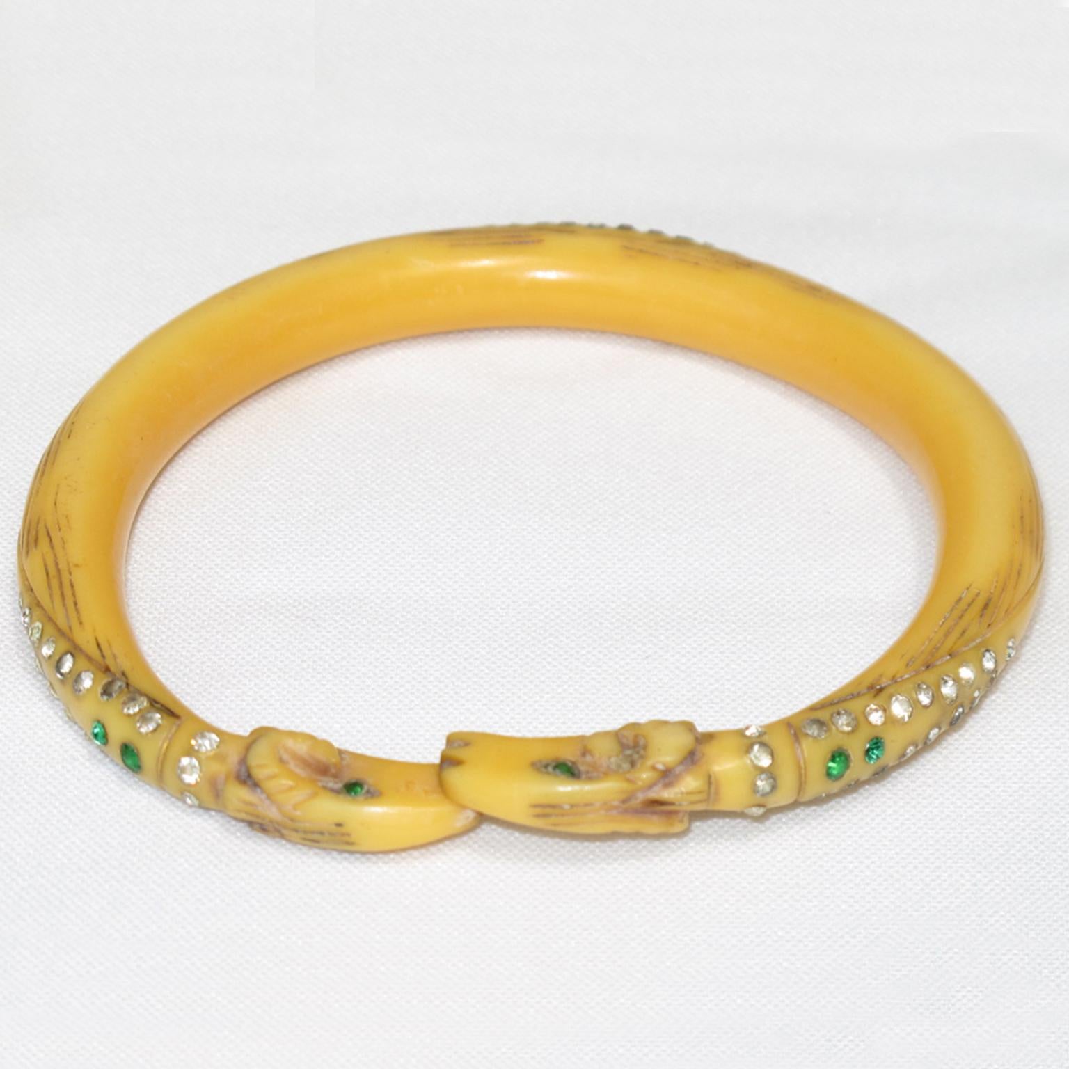 Se trata de un raro y precioso brazalete Art Nouveau de celuloide fabricado en Francia en la década de 1910. La pieza presenta un diseño de doble cabeza de carnero tallado a mano, complementado con brillantes de cristal que adornan la pulsera. La