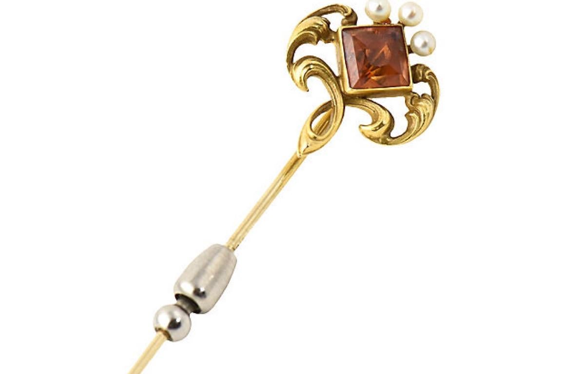 Art Nouveau 14K gold stickpin brooch of intertwined scrolls surrounding a brilliant orange citrine. The intricate, flowing design is accented with three small pearls. Made by Whiteside & Blank, circa 1900. Pin is secured with a sliding metal guard.