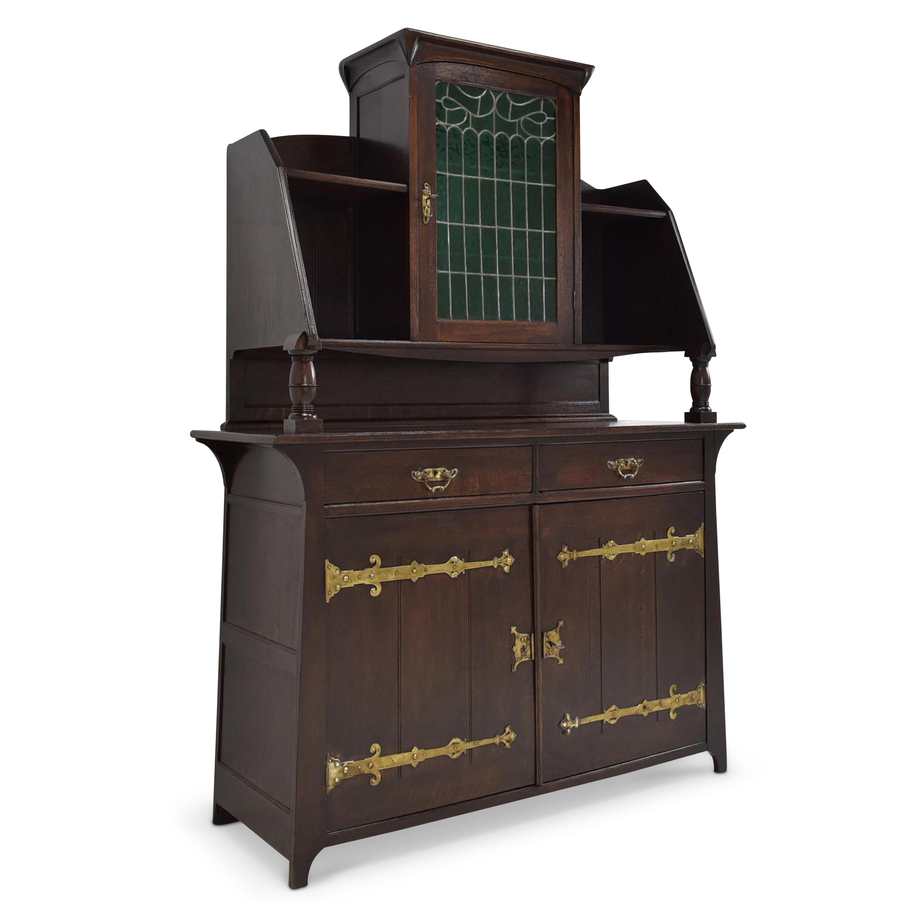 Buffet cabinet restored Jugendstil Art Nouveau around 1920 solid oak

Features:
Single-door top with open compartments on double-door base with two drawers
High quality
Drawers pronged
Original fittings
Original stained glass
Organically
