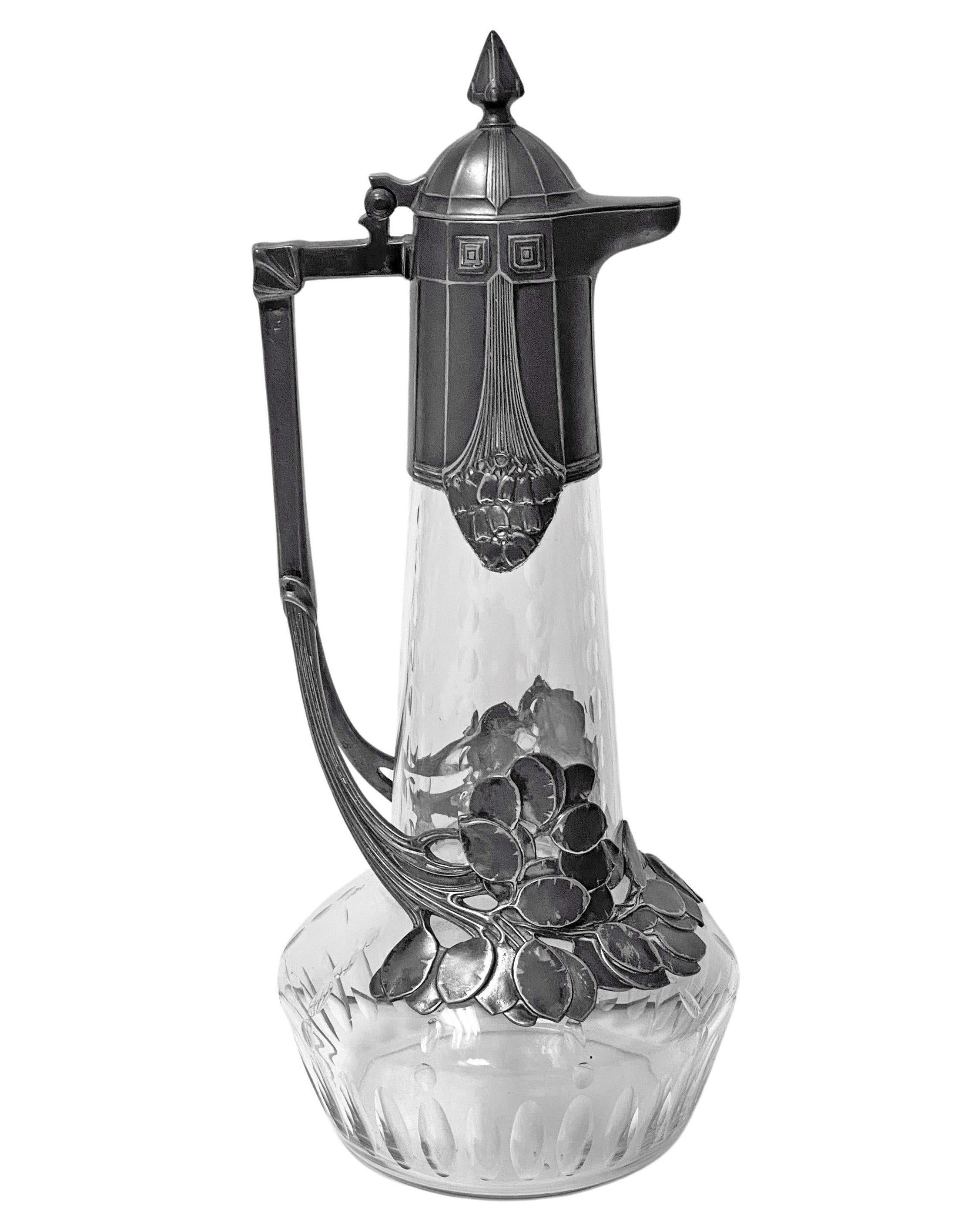 Large WMF Pewter and etched glass Claret Jug Germany C.1909. Art Nouveau Honesty Pod decoration to the pewter. Full WMF marks to handle and 28 1/0 inside cover. Height: 14.5 inches. Width: 6 inches. Good patina. Example illustrated WMF 1909